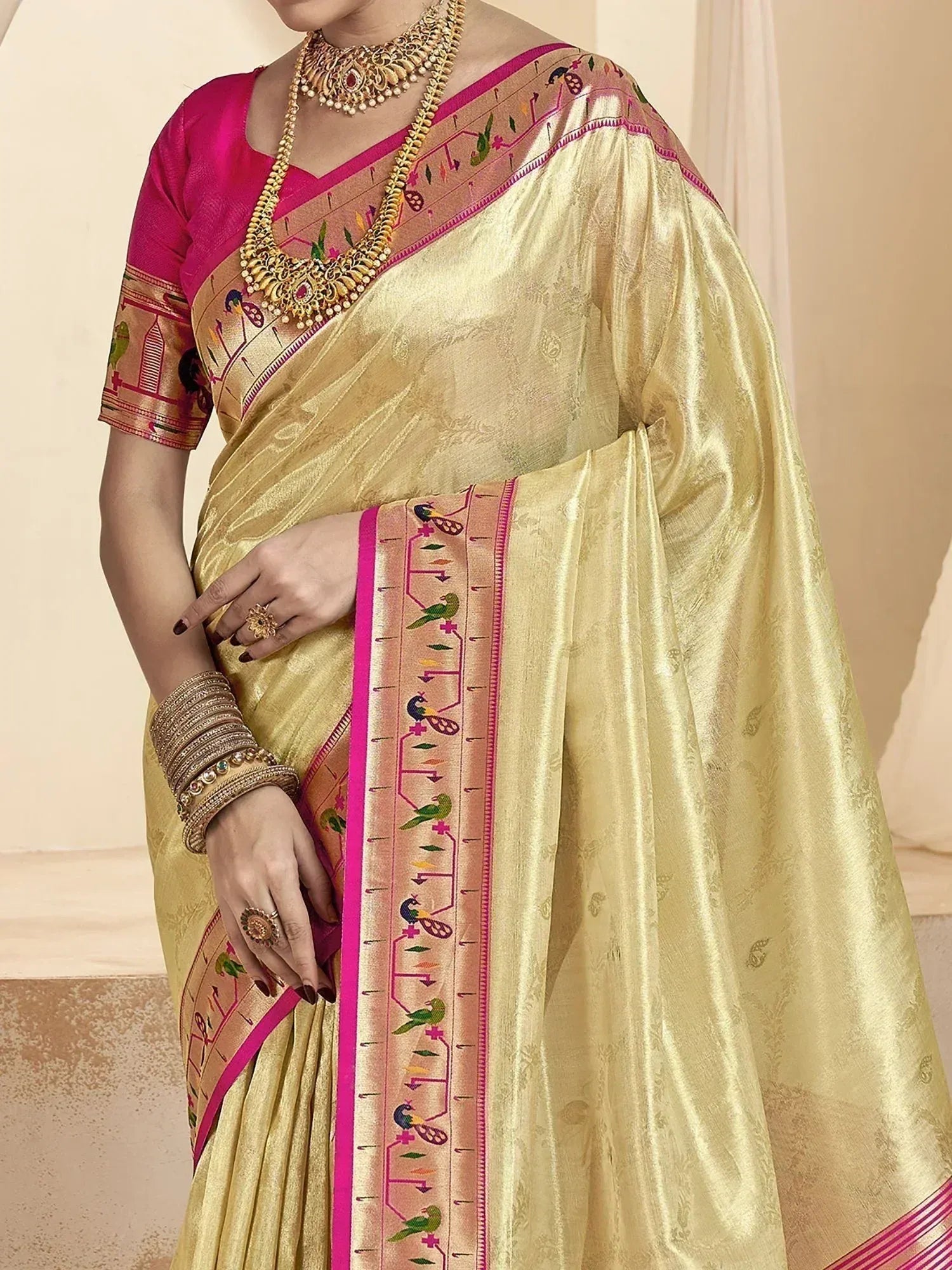 Elegant gold saree with pink border and bird motifs, paired with matching blouse and traditional jewelry