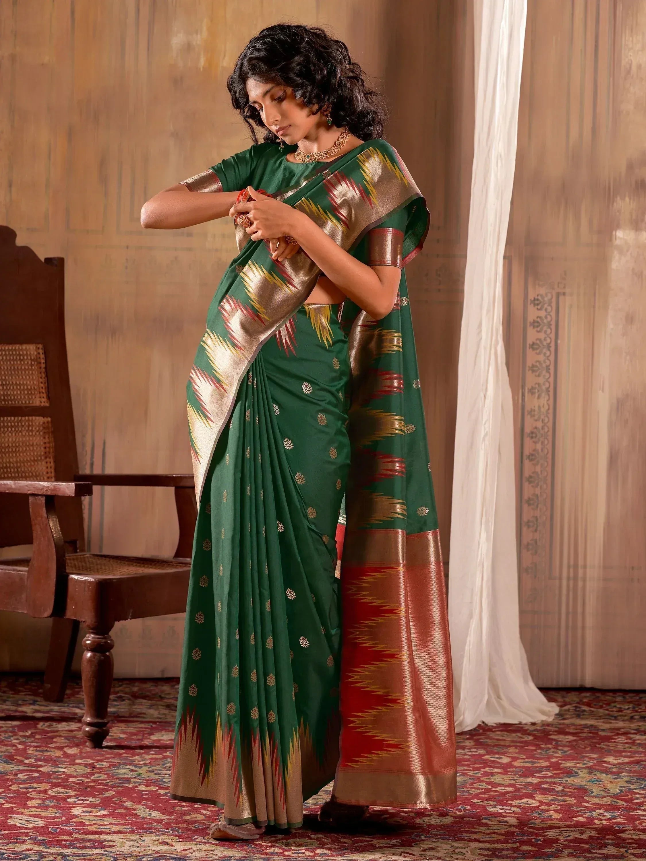 Woman in green ethnic saree with gold and red border, traditional Indian wear
