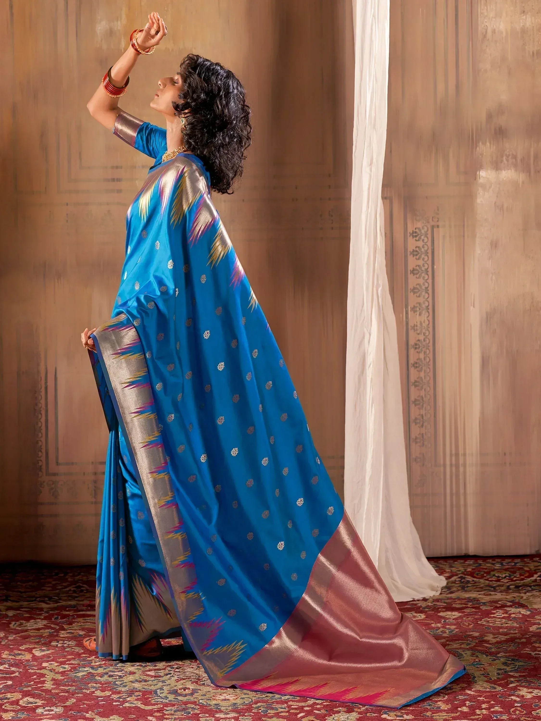 Blue silk saree with gold motifs and ikat border, styled with traditional jewelry for ethnic wear