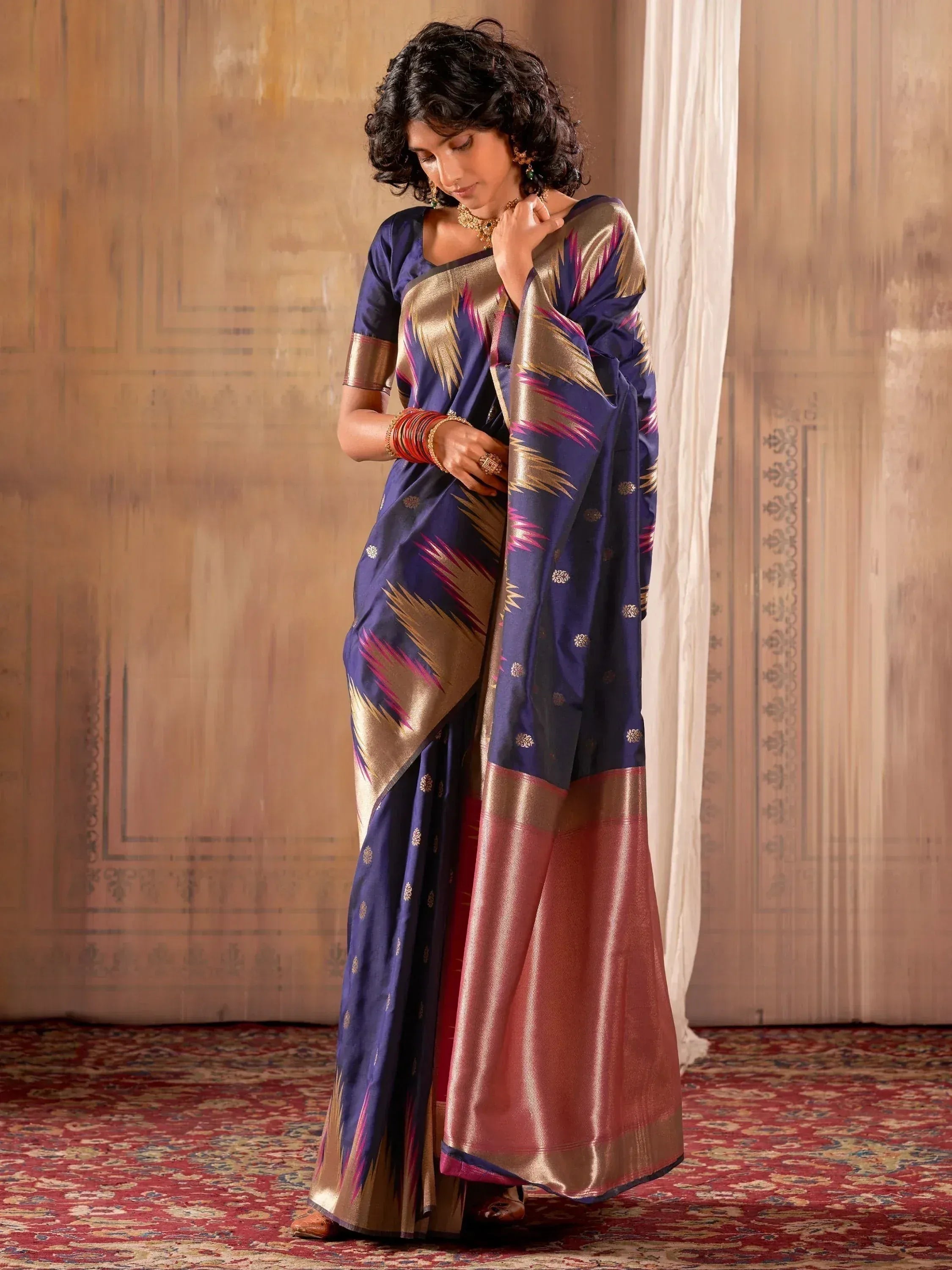 Woman in elegant navy blue silk saree with gold and pink ikat patterns, traditional Indian ethnic wear