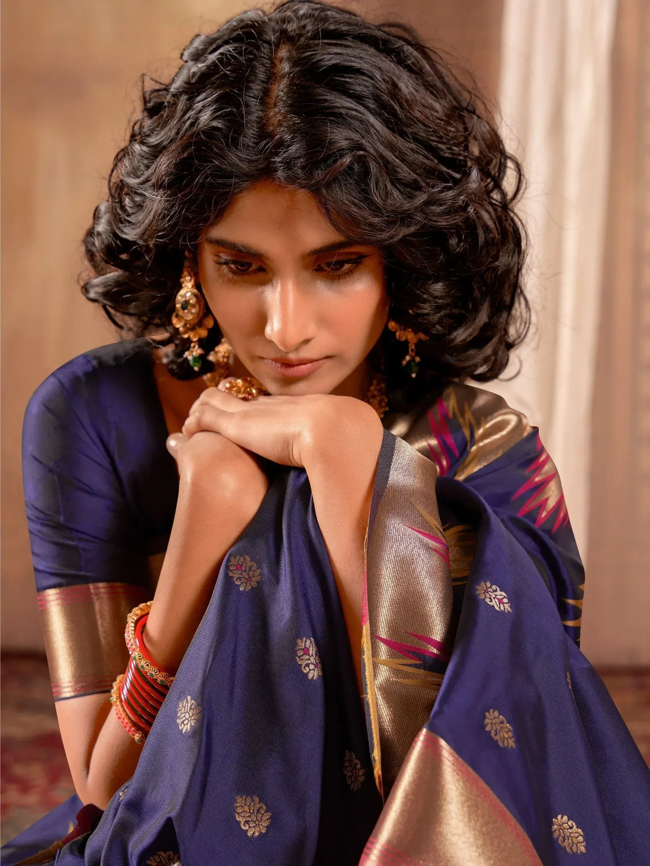 Elegant woman in navy blue designer saree with gold embroidery and traditional jewelry, showcasing Indian ethnic wear.