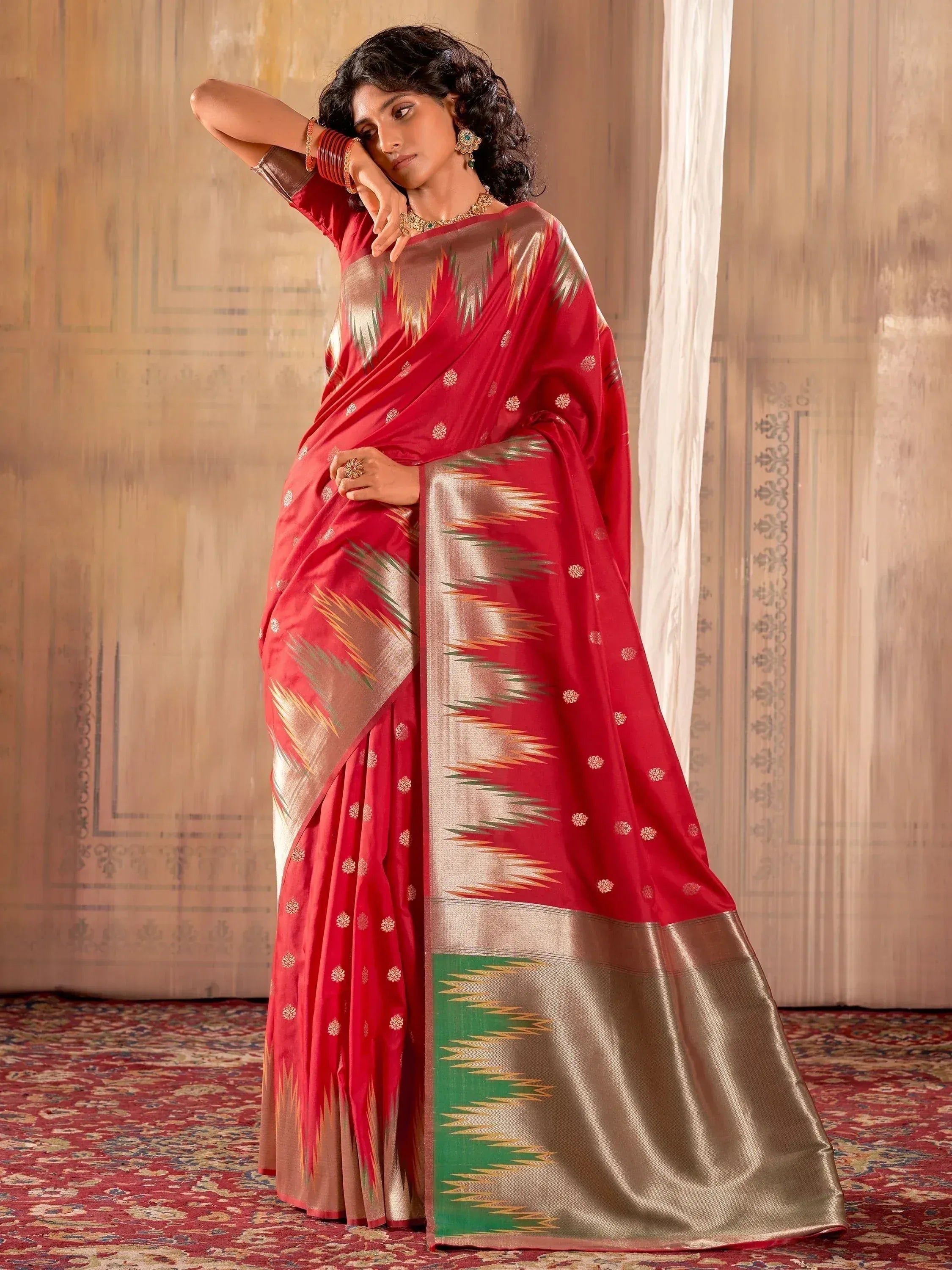 Red ethnic saree with gold ikat border and green accents, styled with traditional jewelry
