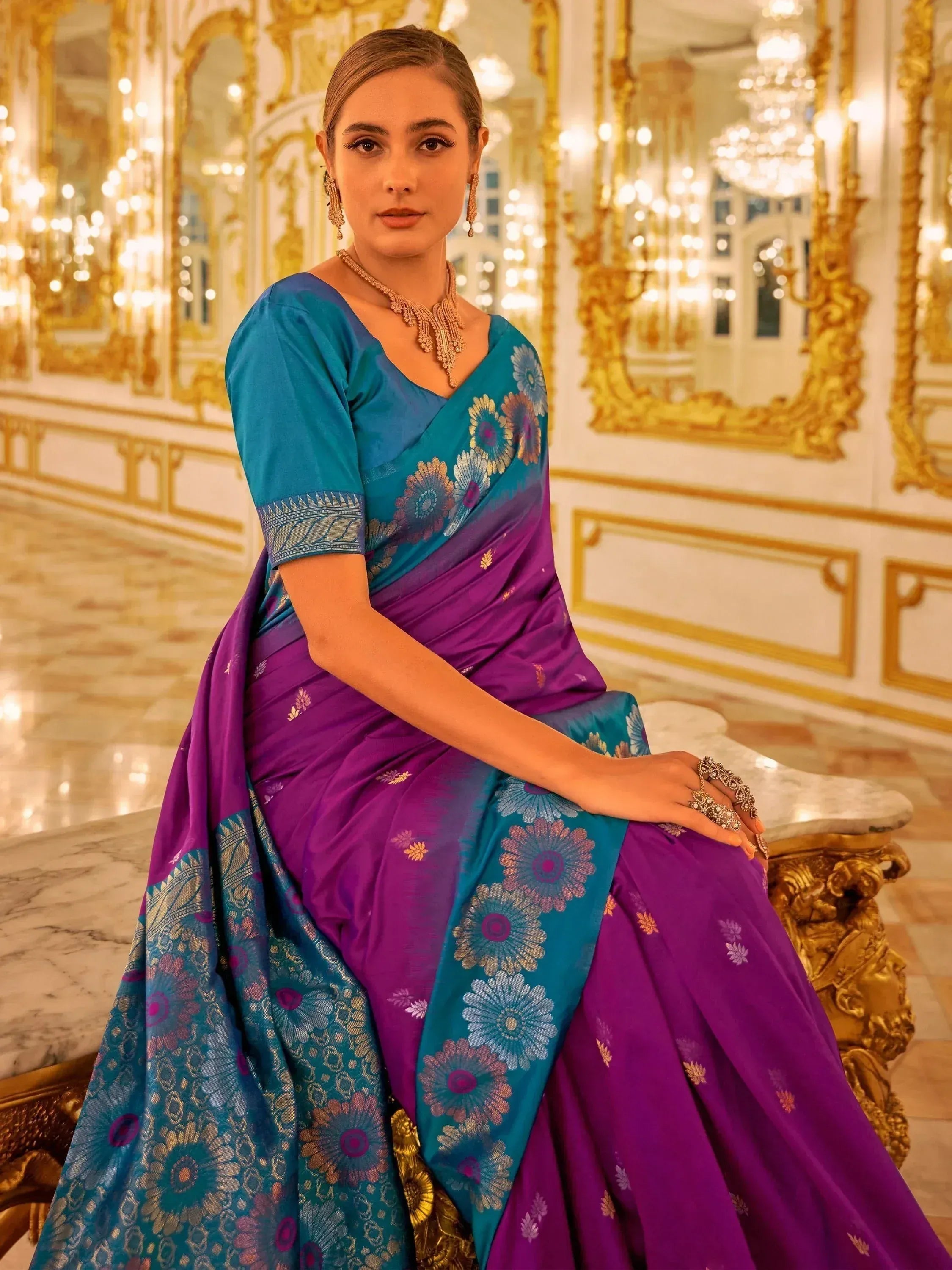 Woman in elegant purple and teal floral saree with gold embroidery, styled for festive occasions