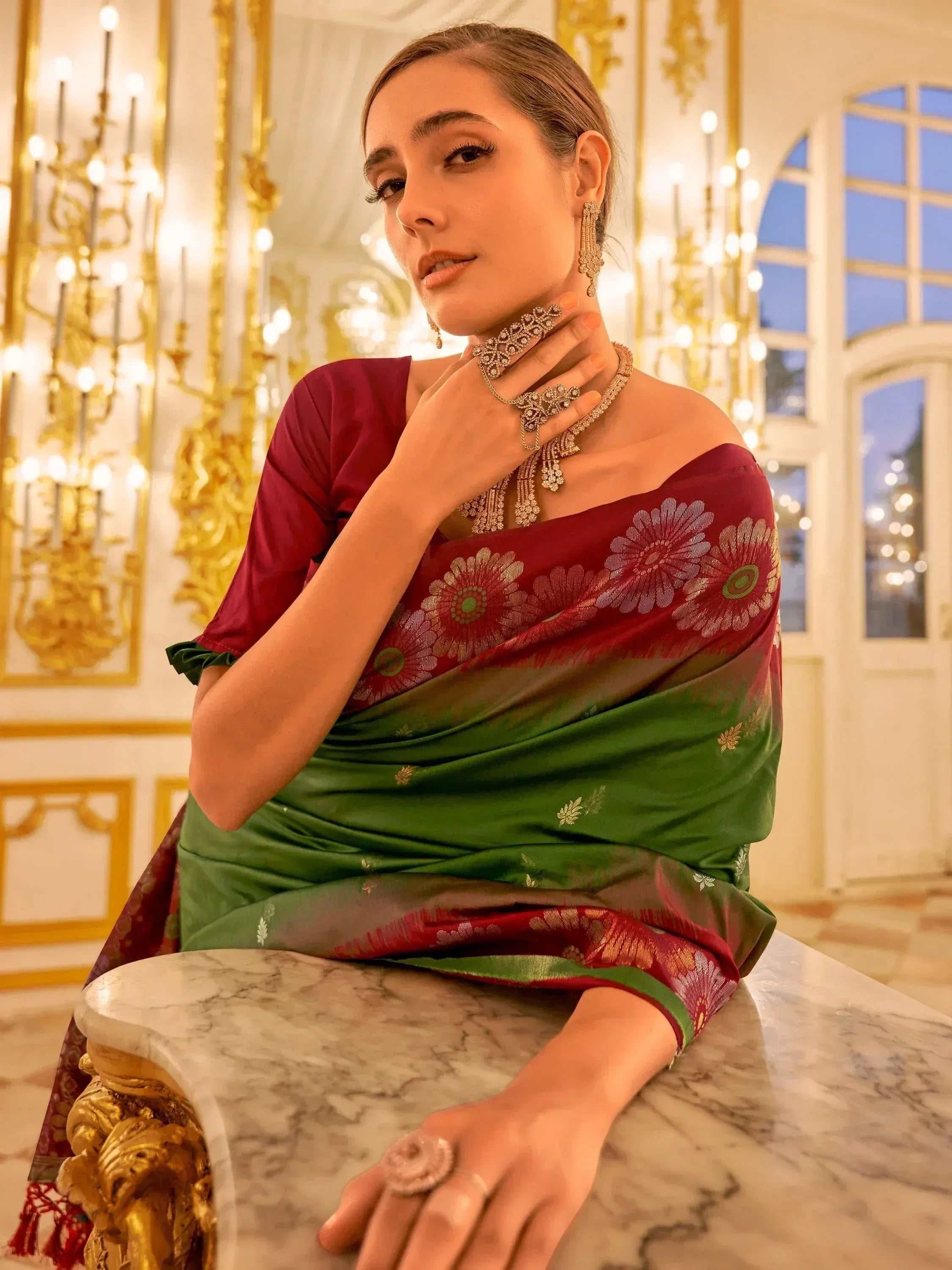 Elegant woman in maroon and green floral saree with gold jewelry, showcasing Indian ethnic wear.