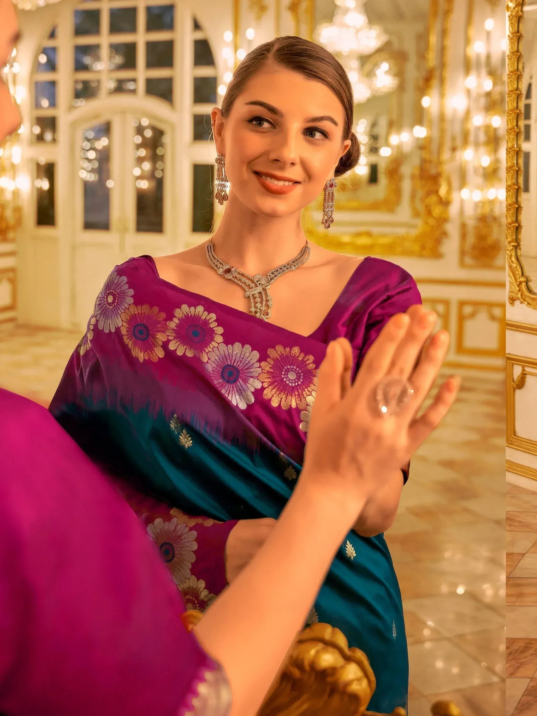 Woman in purple and teal designer saree with floral embroidery, elegant jewelry, in luxurious palace setting