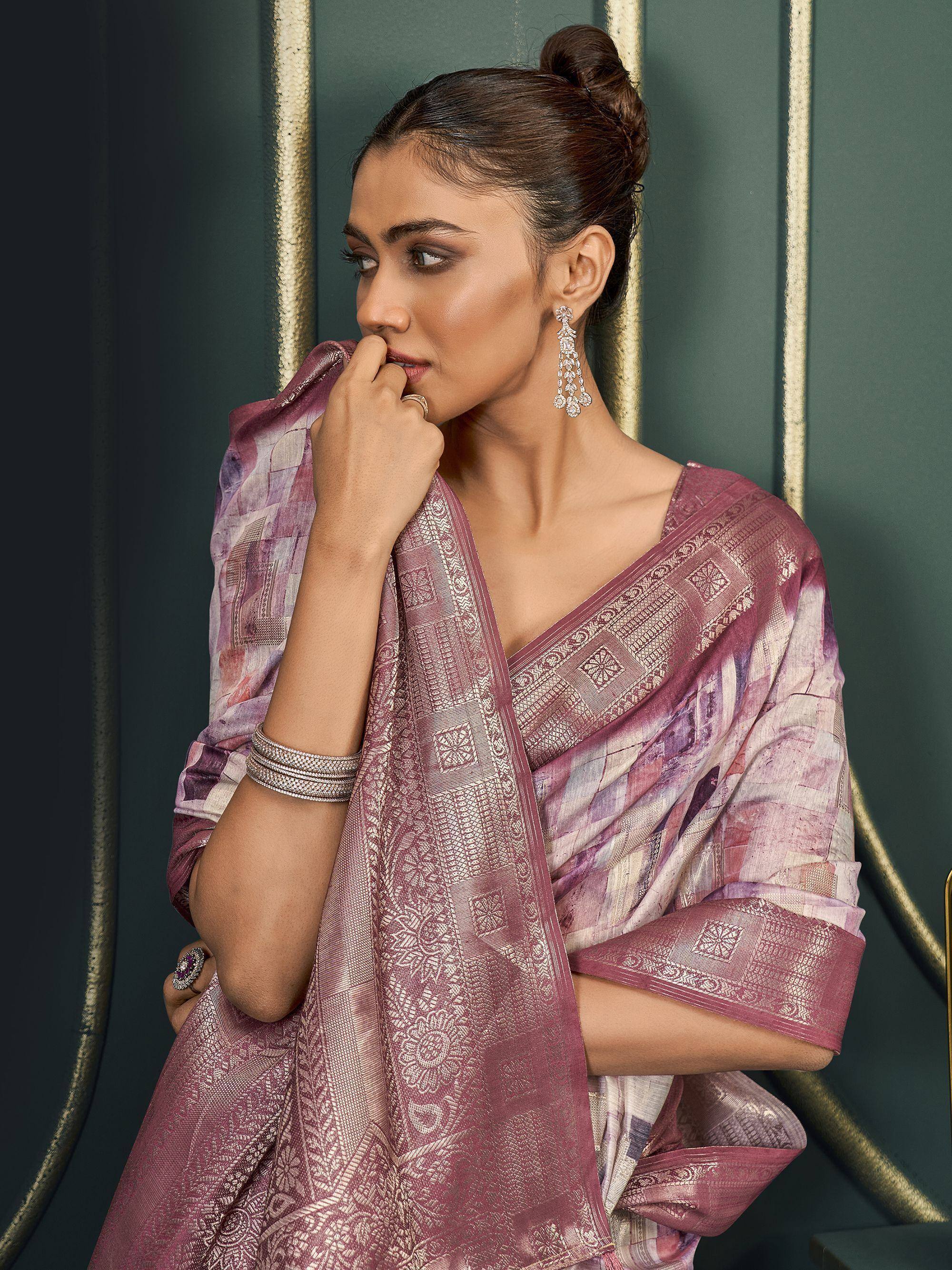 Woman in elegant purple and gold designer saree with intricate patterns, styled with jewelry for ethnic occasions.