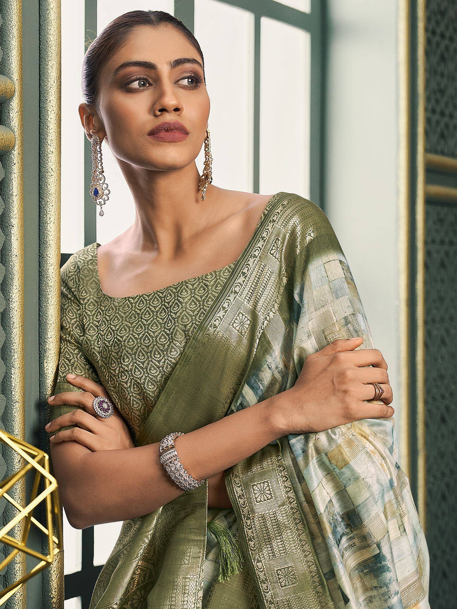 Elegant olive green designer saree with intricate patterns, paired with statement jewelry for ethnic wear.