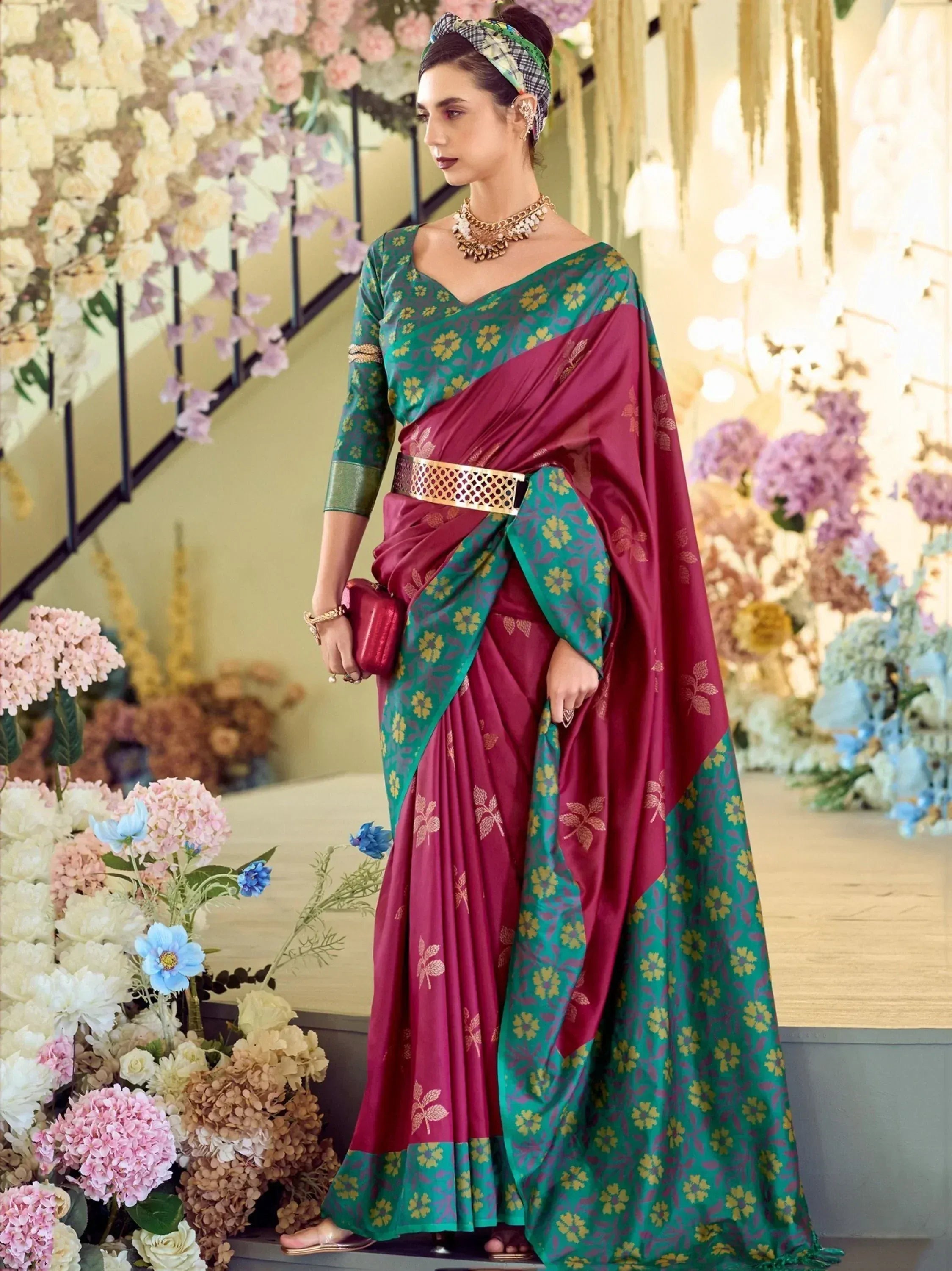 Woman in maroon and green floral saree with gold belt, styled for ethnic occasions