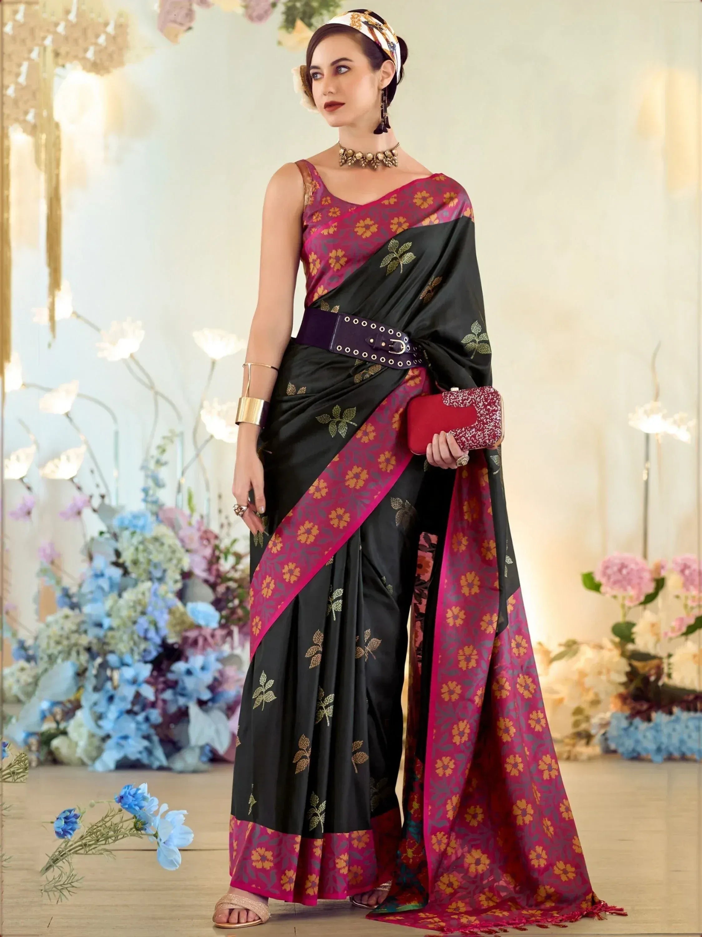 Black and magenta floral saree with gold embroidery, styled with belt and clutch for ethnic occasions