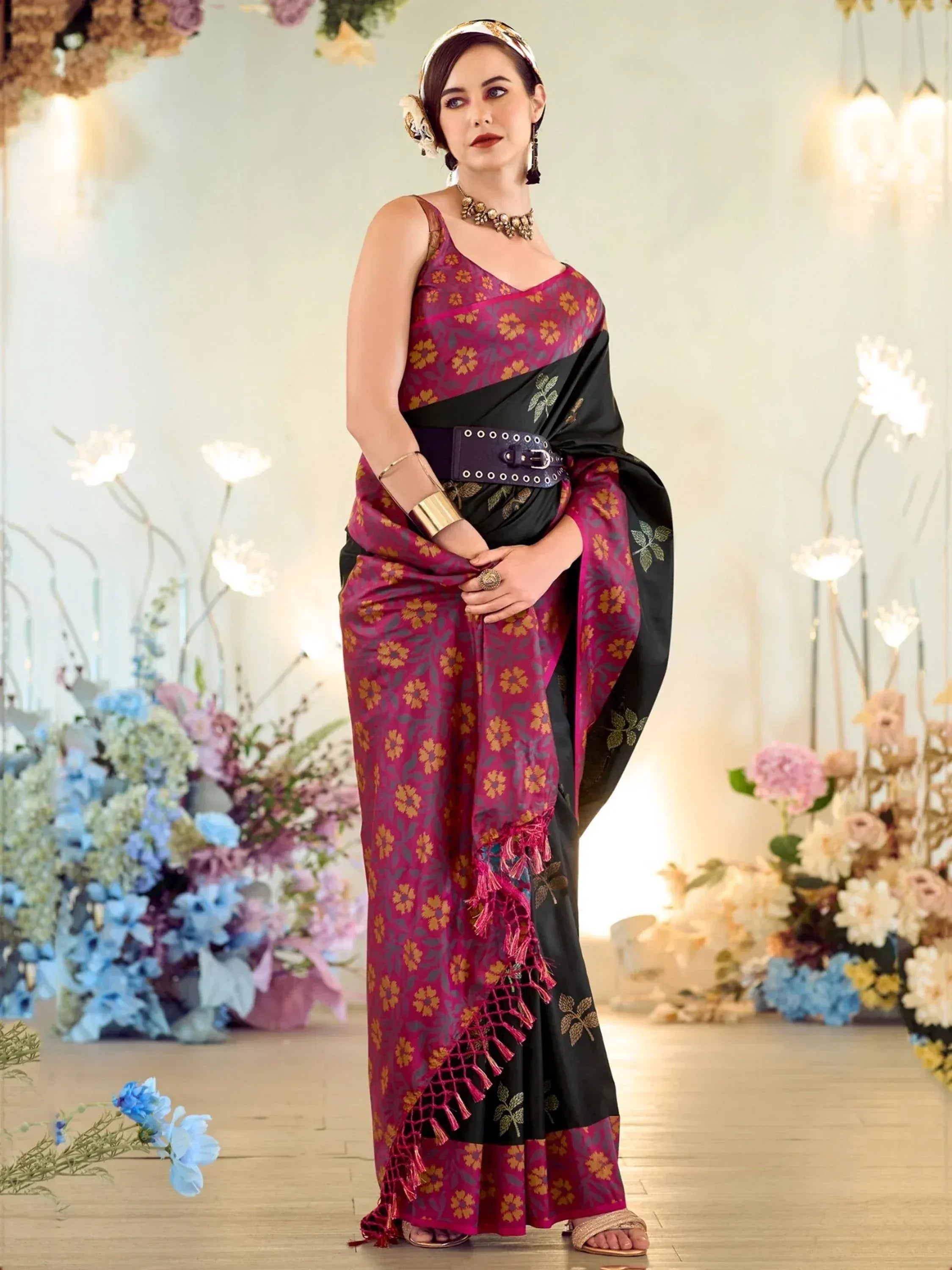 Woman in maroon and black floral saree with gold embroidery, styled with belt and ethnic jewelry for festive occasions