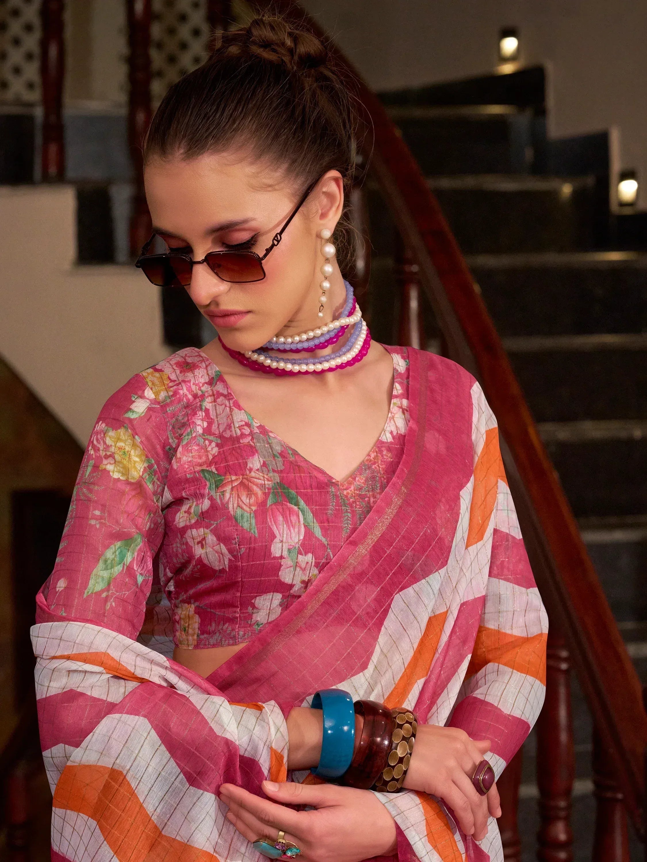 Floral pink saree with striped border, styled with pearl jewelry and sunglasses