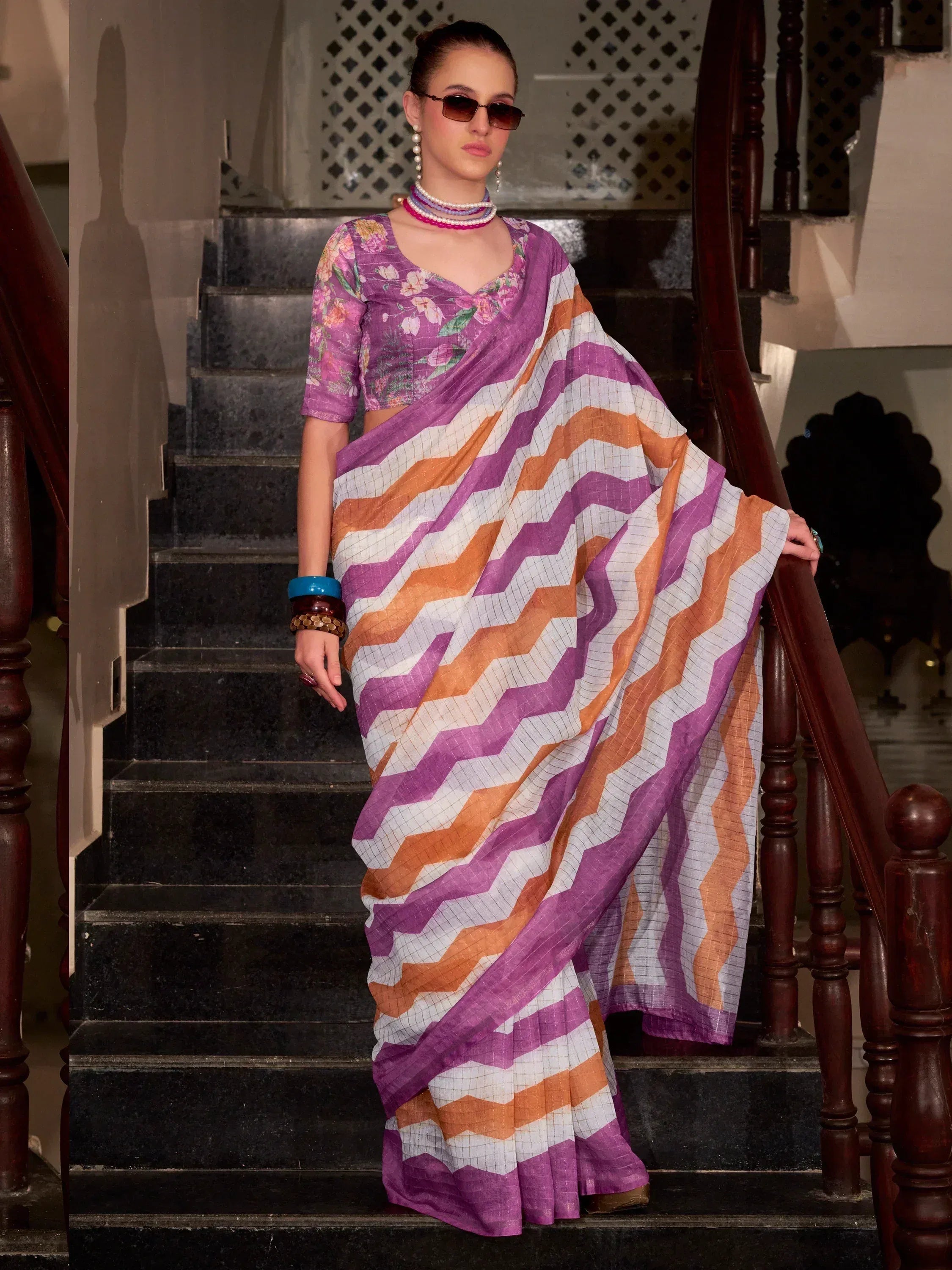 Purple and orange zigzag saree with floral blouse, styled on stairs