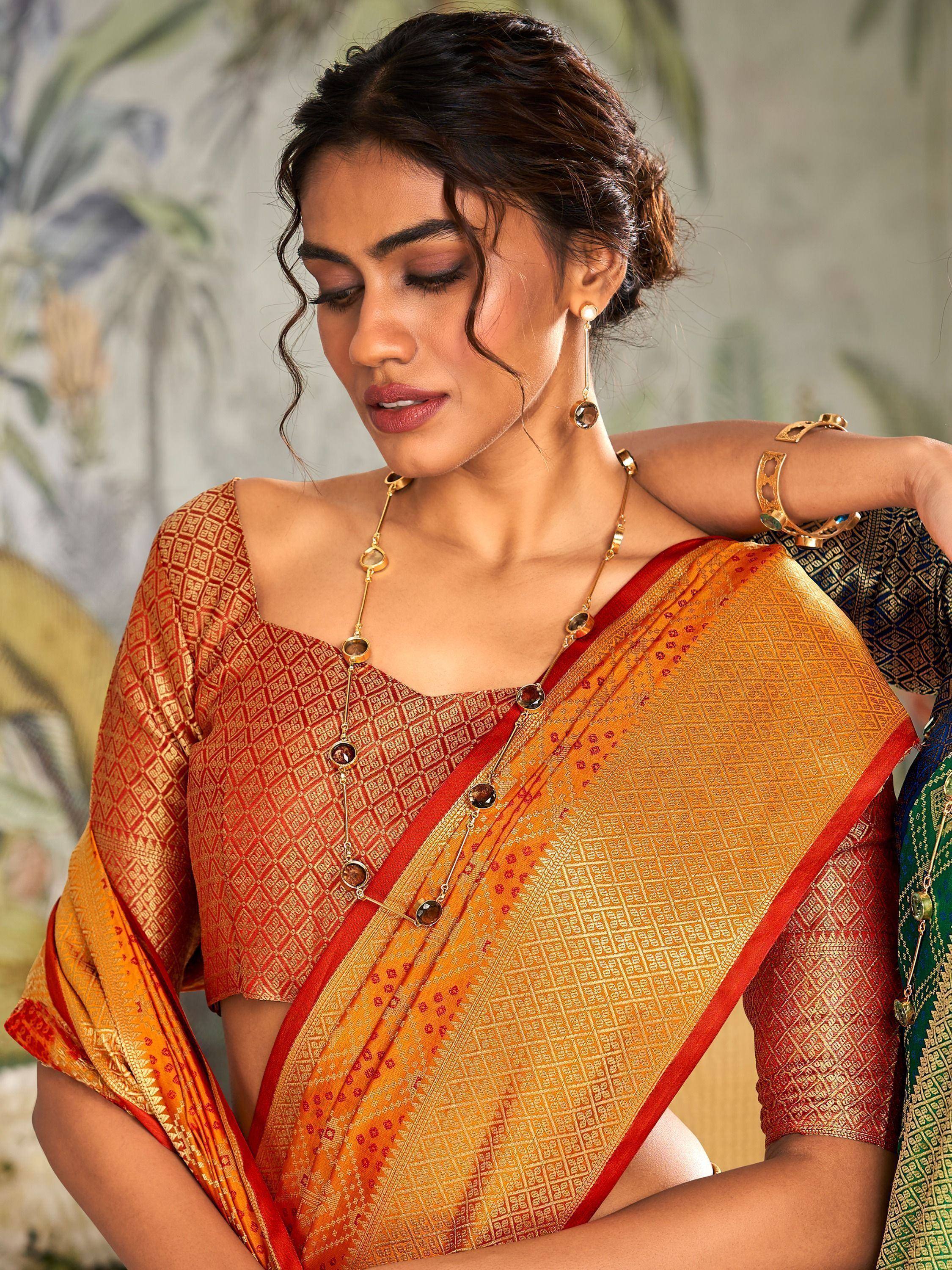 Woman in orange and red patterned saree with gold jewelry, ethnic Indian wear