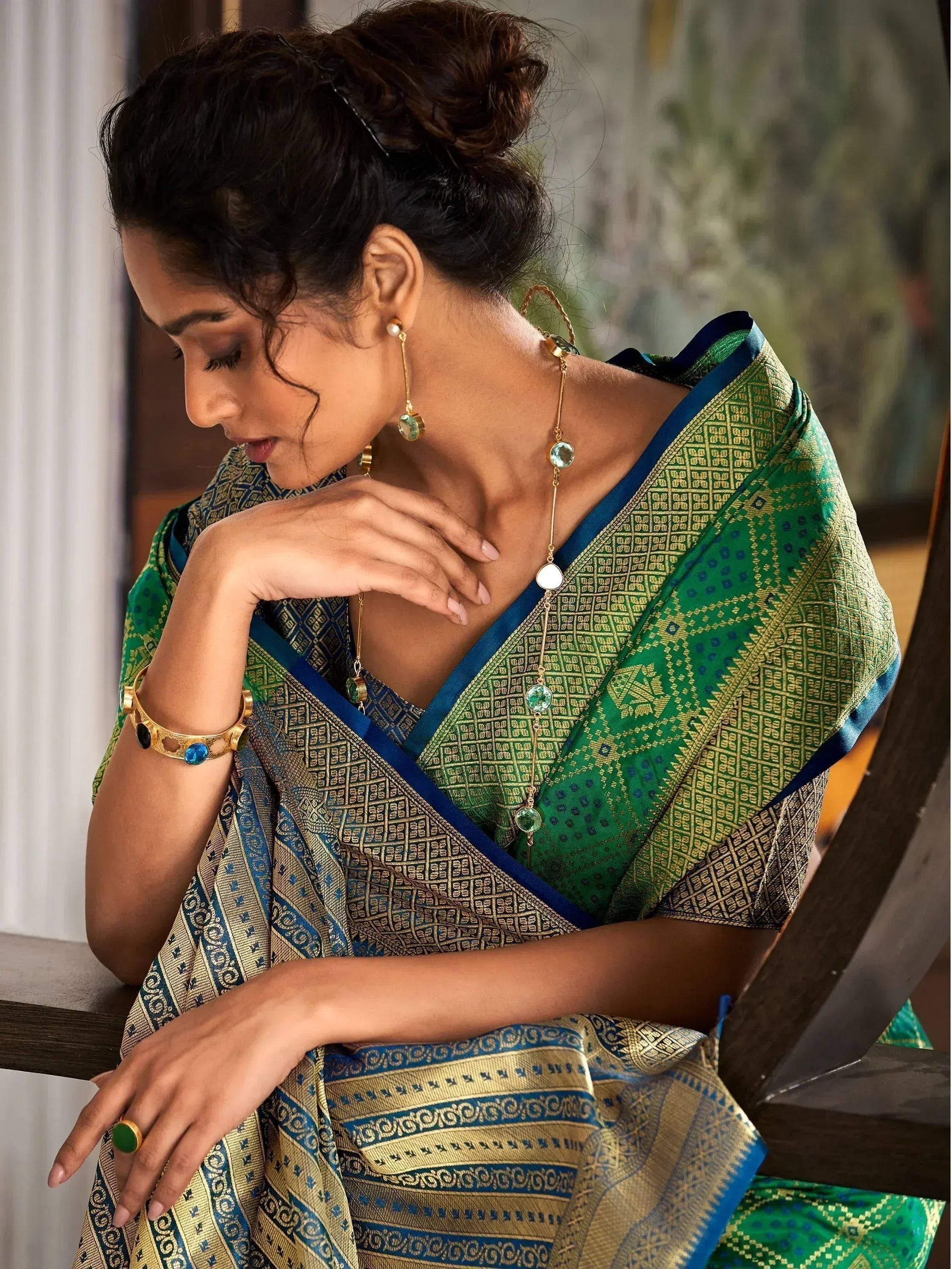 Woman in elegant green and blue patterned saree with gold jewelry, showcasing Indian ethnic wear.