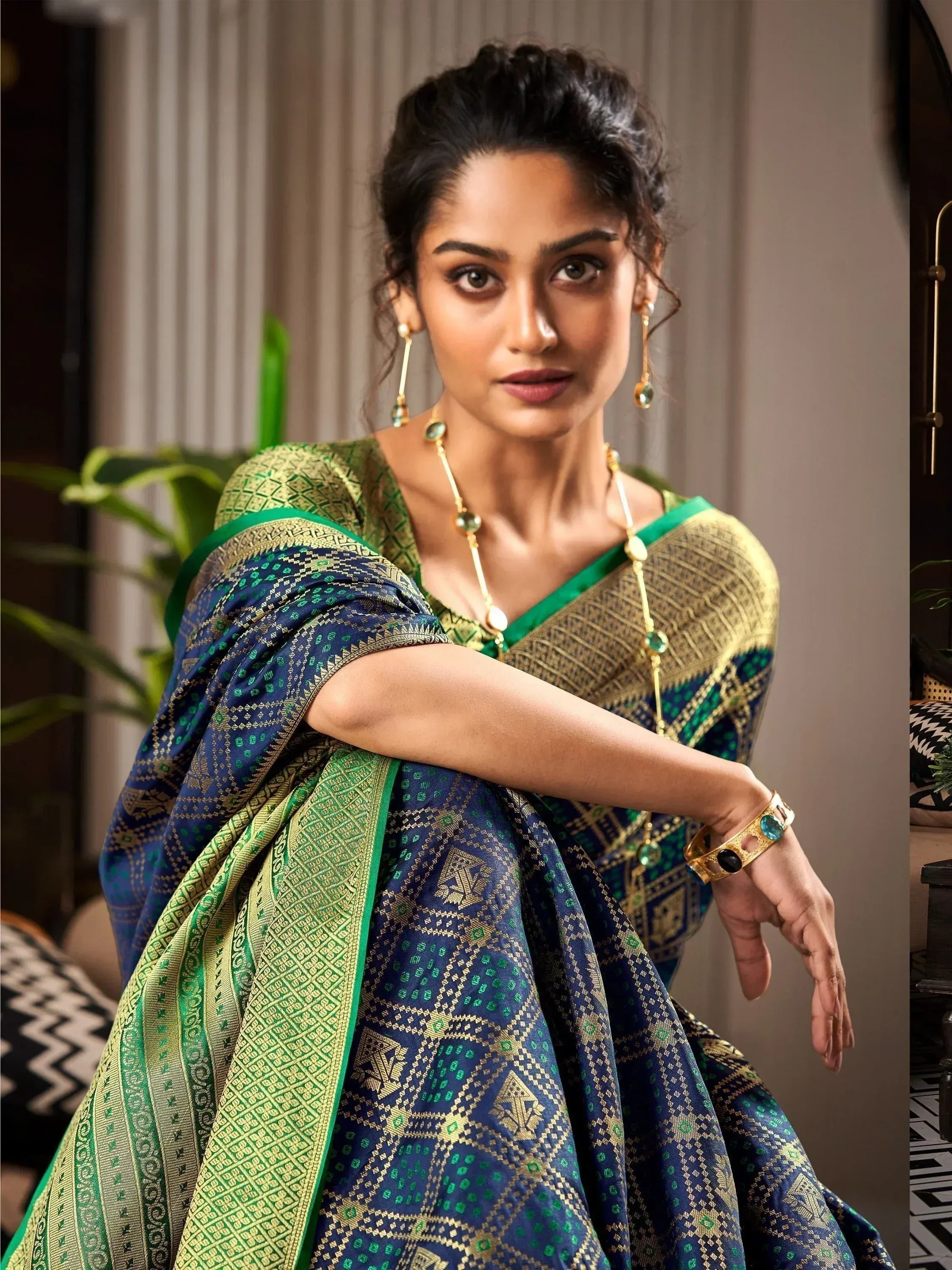Woman in elegant blue and green designer saree with gold embroidery, perfect for Indian ethnic wear occasions.