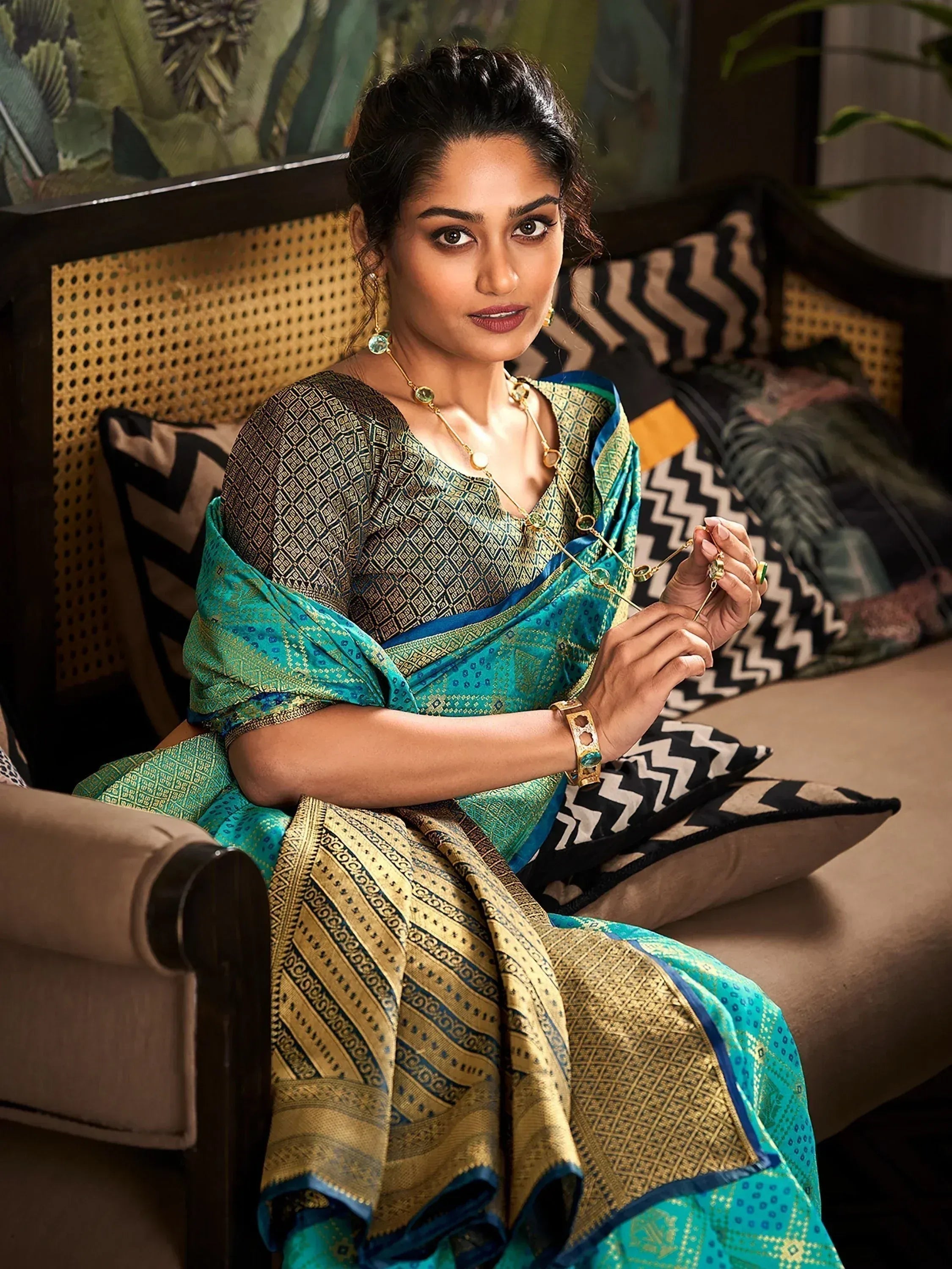 Woman in elegant teal and gold ethnic saree with intricate patterns, styled with traditional jewelry.