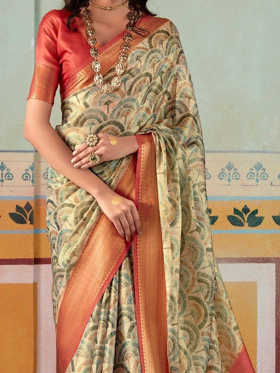 Elegant printed saree with peacock motif, paired with coral blouse and gold jewelry for ethnic wear