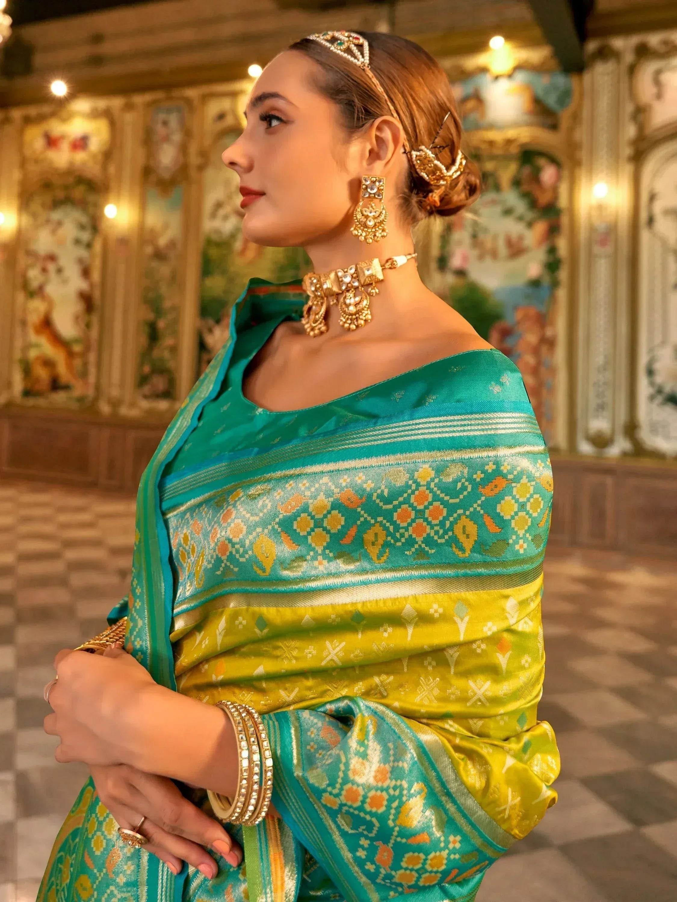 Woman in teal and yellow designer saree with gold jewelry, ethnic wear for festive occasions