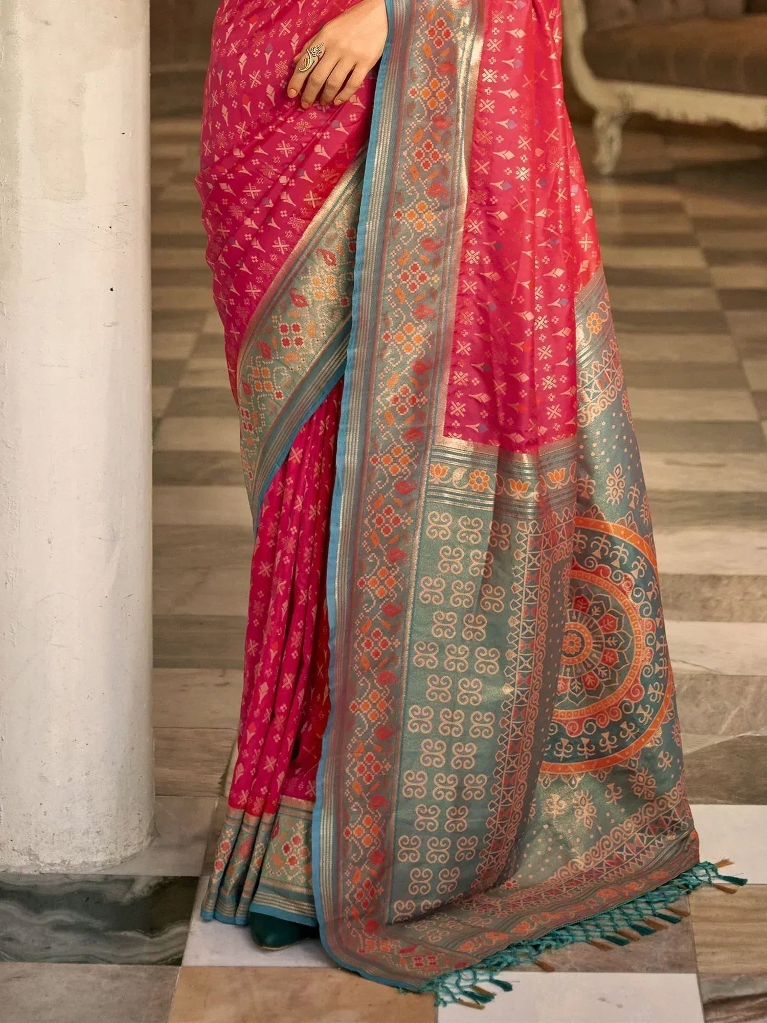 Pink and teal designer saree with intricate ethnic patterns and gold zari border, perfect for festive occasions