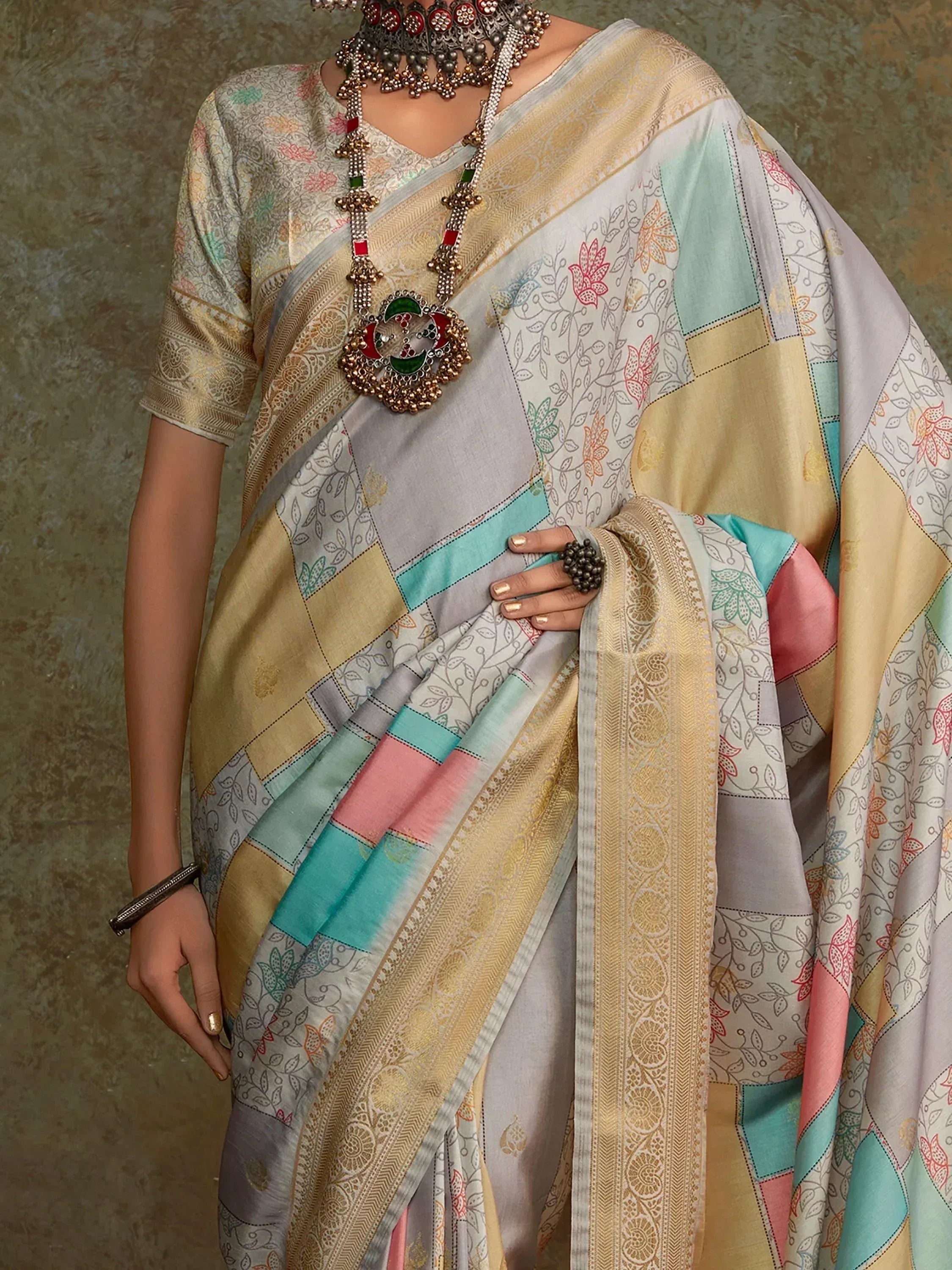 Elegant patchwork saree with floral prints and gold border, paired with traditional jewelry for ethnic wear.
