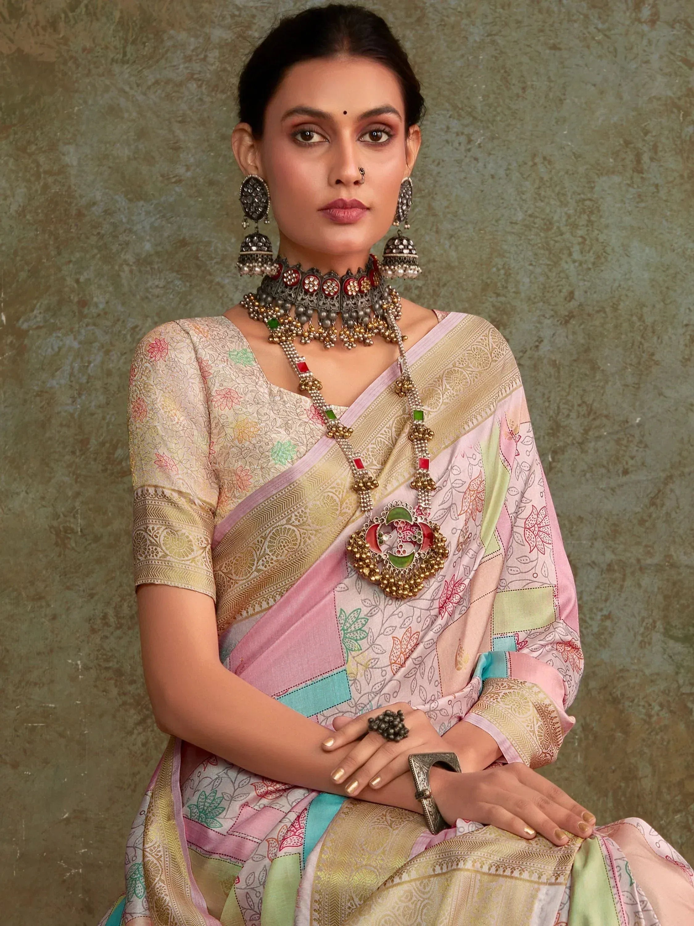 Woman in colorful printed saree with gold embroidery, traditional Indian jewelry, and nose ring