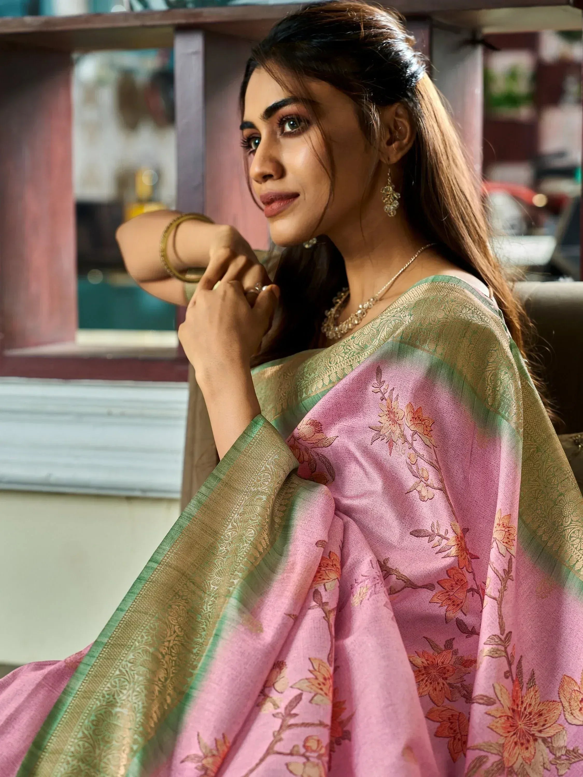 Elegant woman in pink floral saree with gold border, styled with traditional jewelry for ethnic wear.
