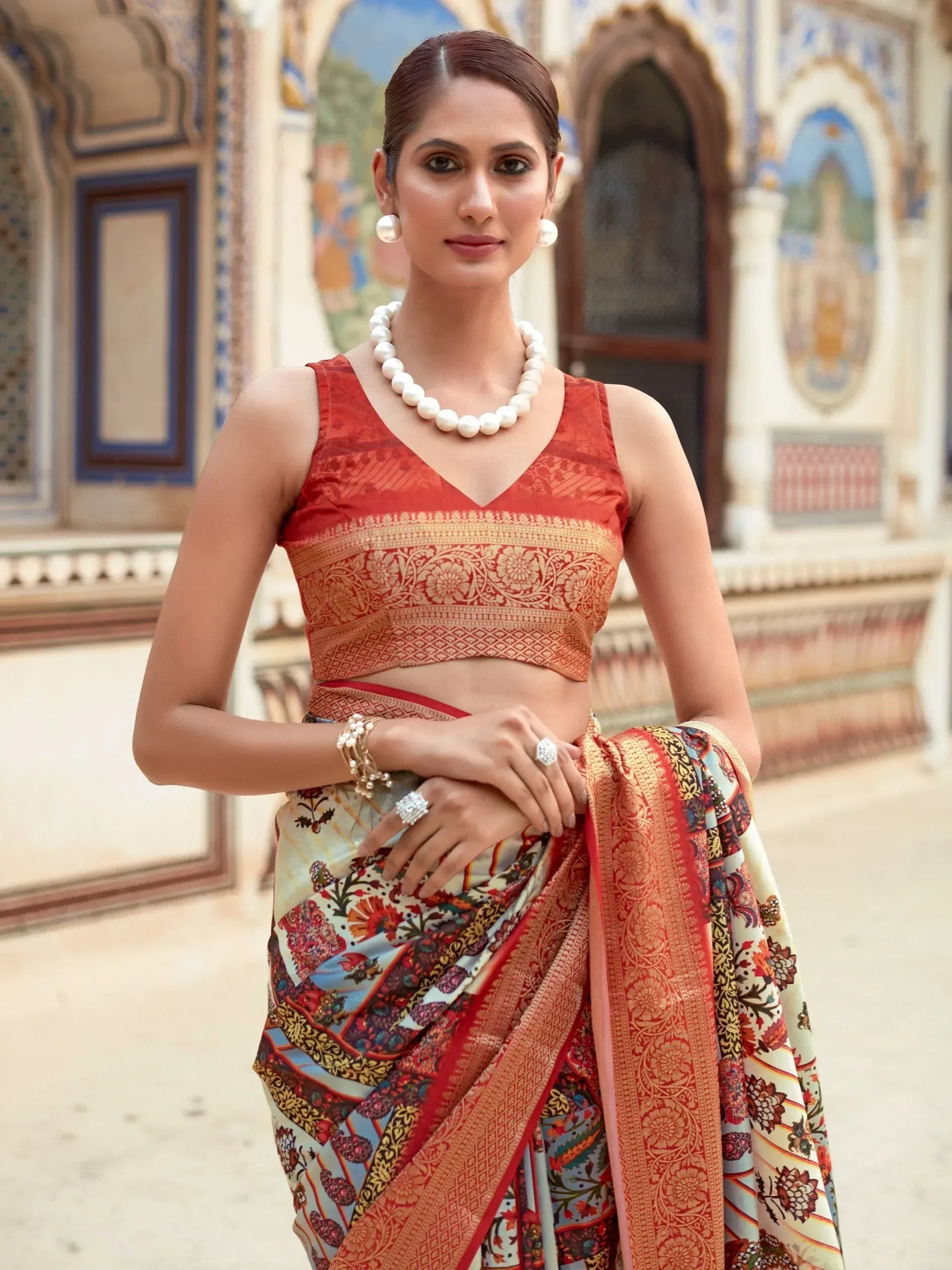 Woman in vibrant floral saree with embroidered red blouse, pearl jewelry, traditional Indian attire