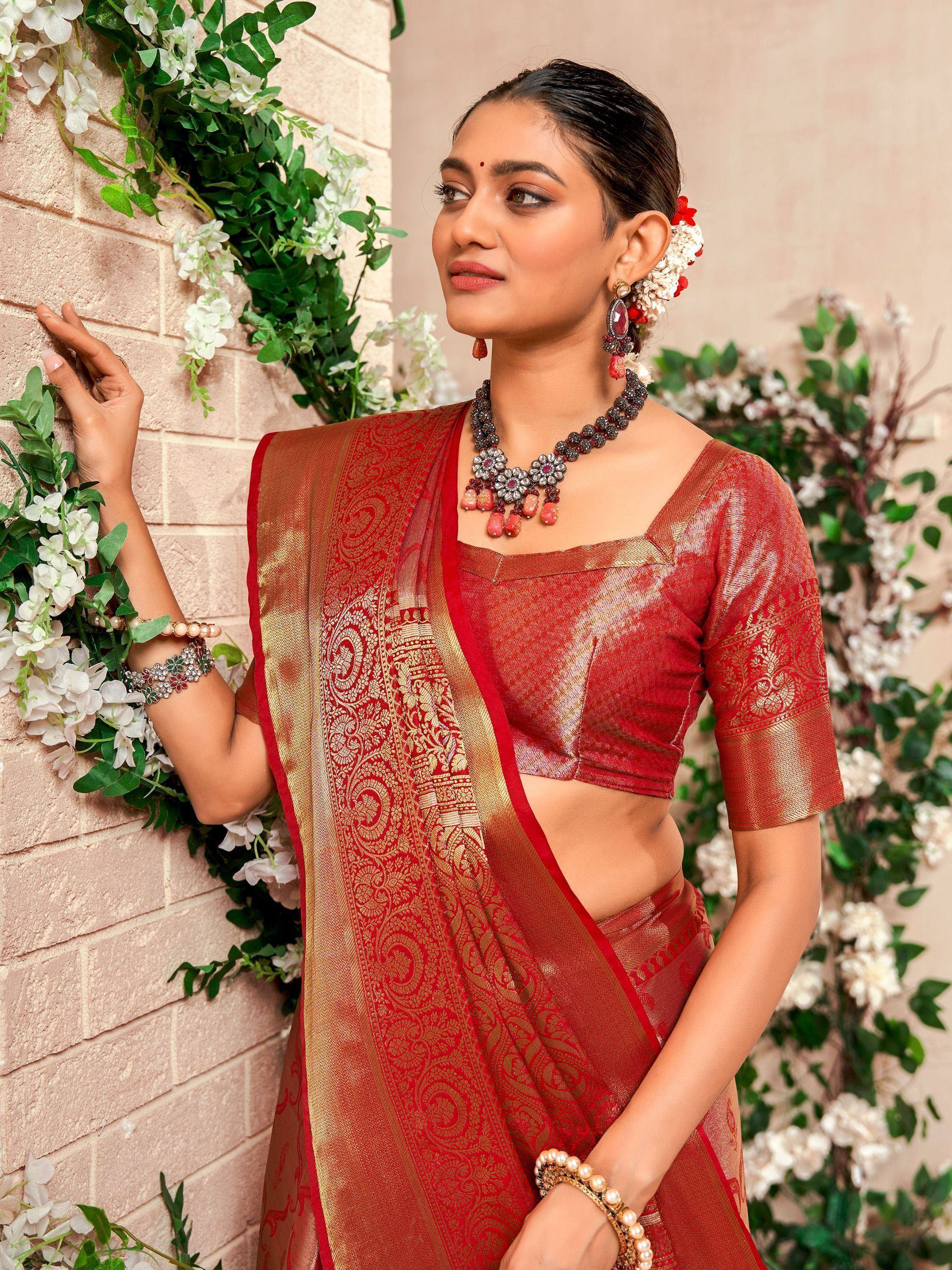 Red and gold designer saree with intricate paisley border, paired with matching blouse and traditional jewelry