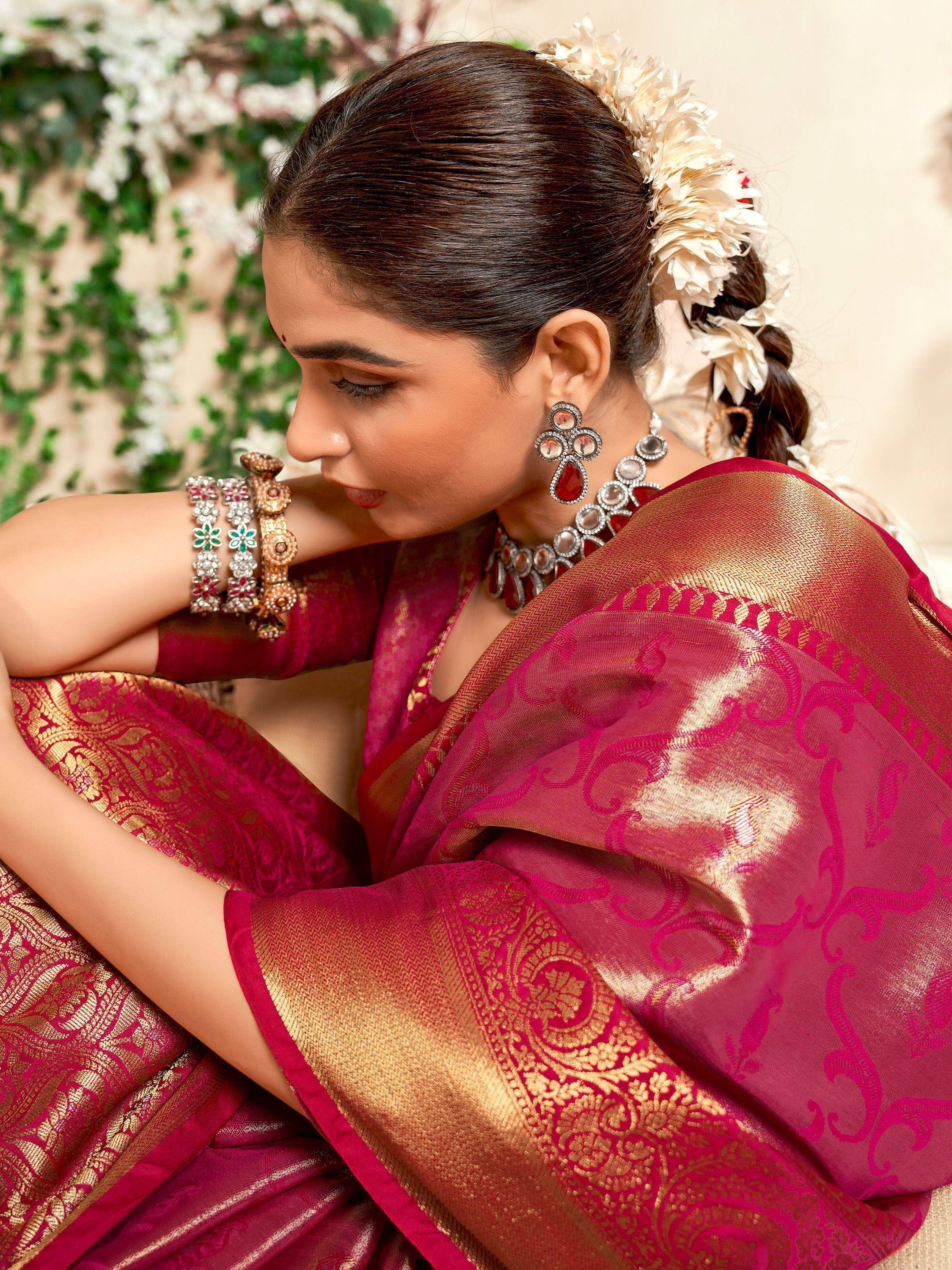 Woman in elegant pink and gold designer saree with floral hair accessory and traditional jewelry