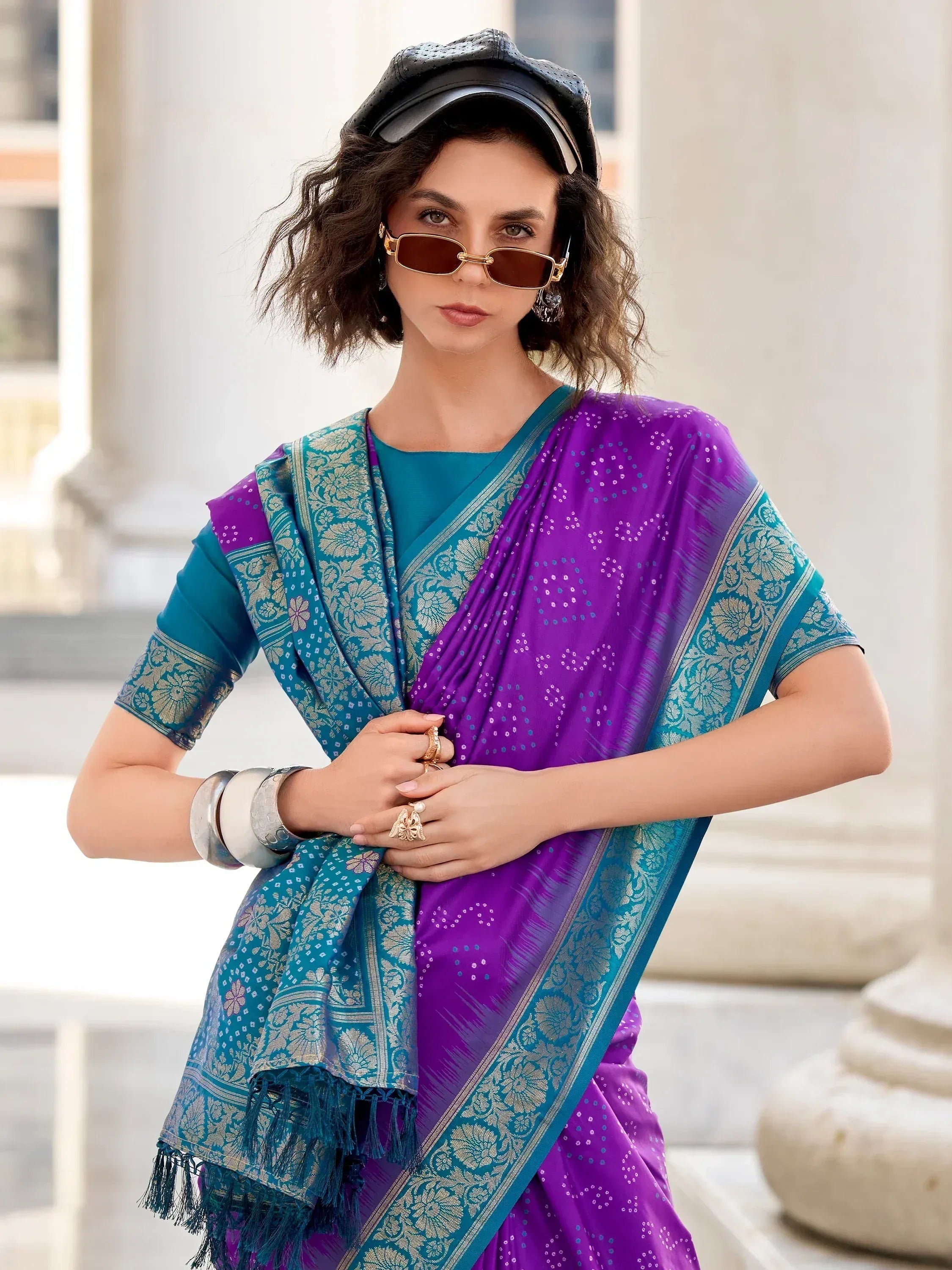 Purple and teal designer saree with floral border, styled with cap and sunglasses for ethnic fashion