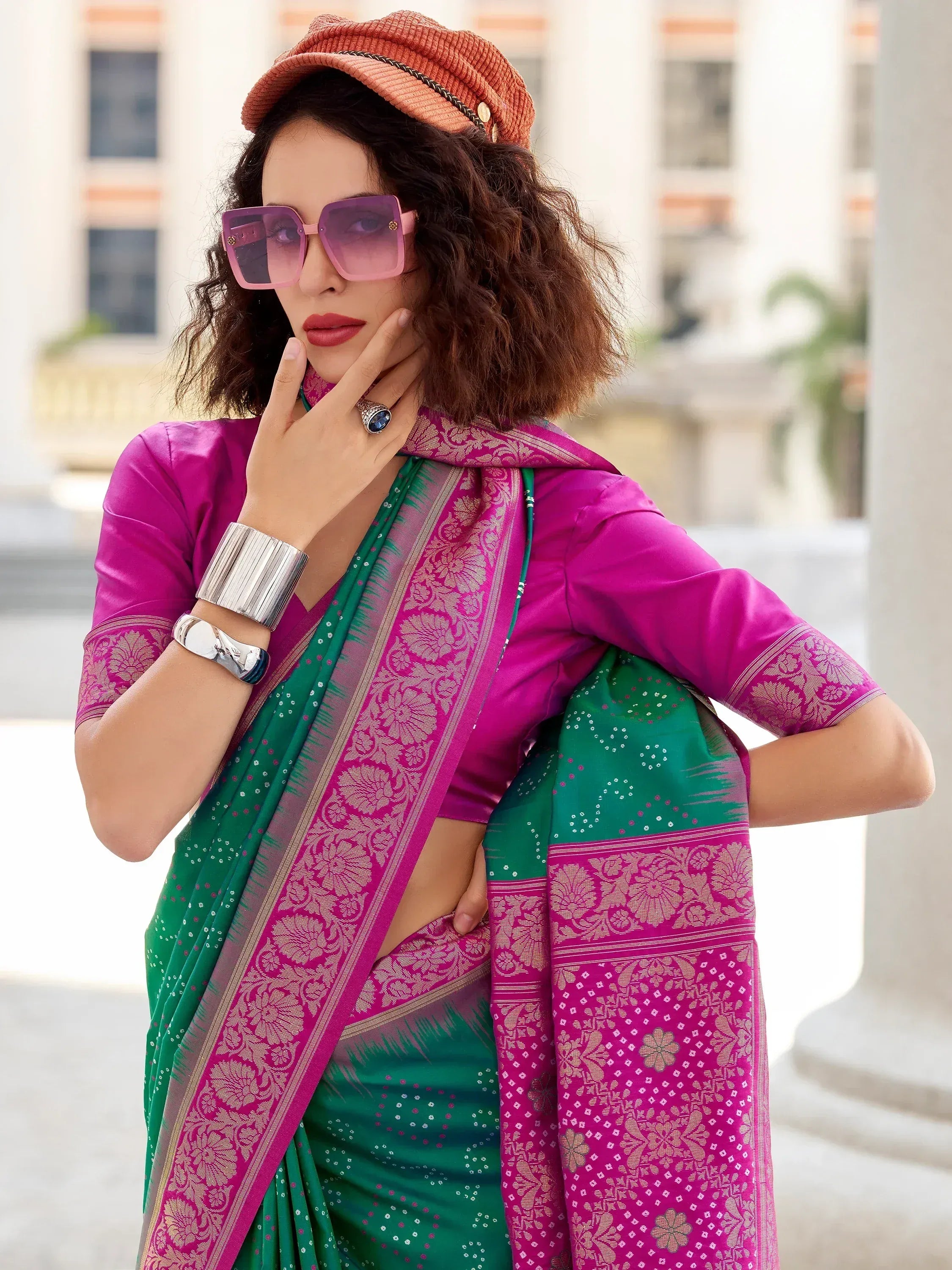 Stylish green and pink saree with gold border, paired with modern accessories and a cap for ethnic fashion.