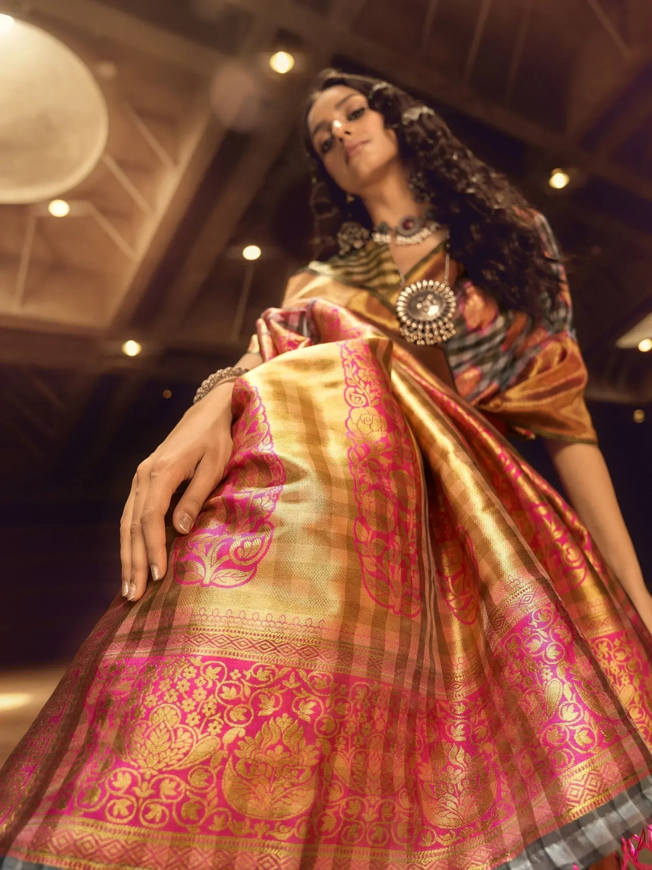 Woman in elegant gold and pink designer saree with intricate floral patterns, perfect for ethnic occasions.