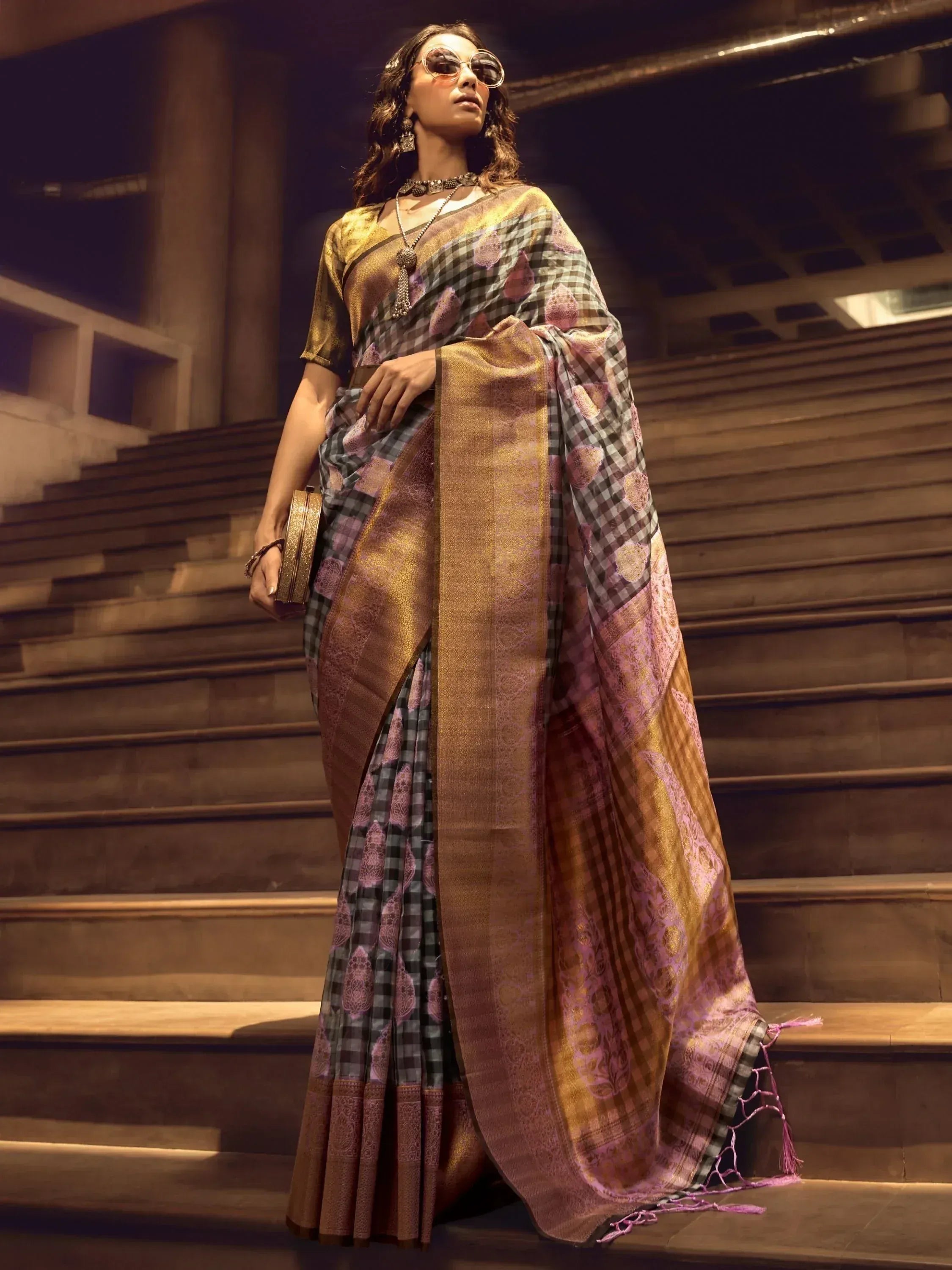 Woman in stylish checkered and gold ethnic saree with purple motifs, standing on stairs