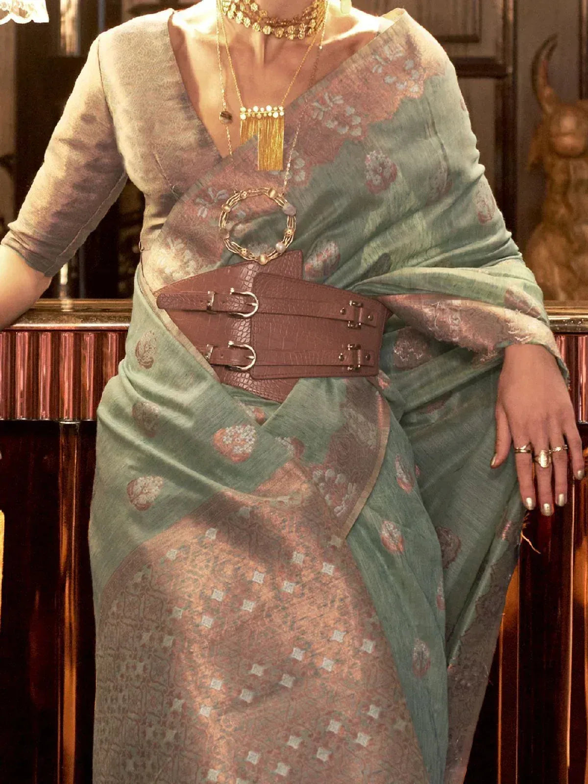 Stylish green floral saree with brown belt, gold jewelry, and ethnic blouse for Indian occasions