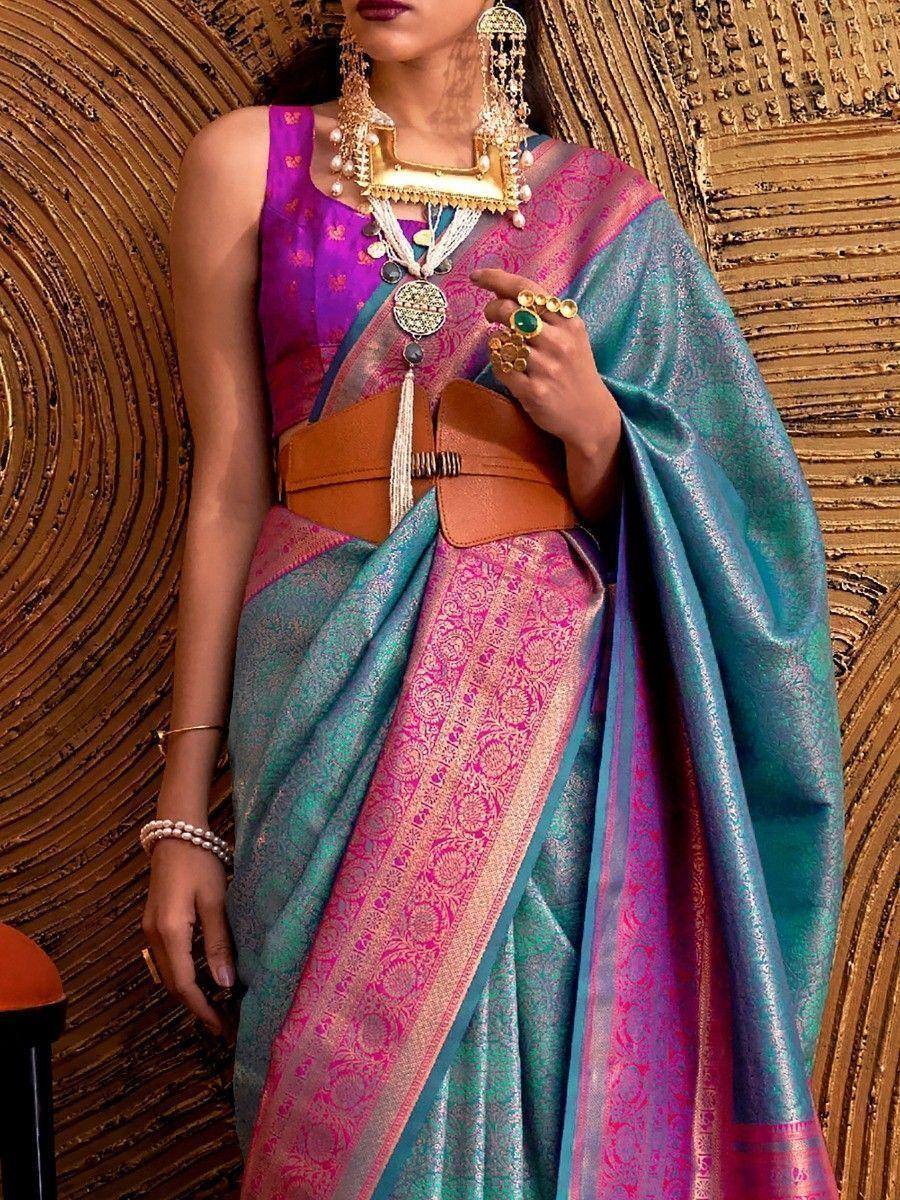 Vibrant teal and pink designer saree with gold embroidery, paired with purple blouse and statement jewelry