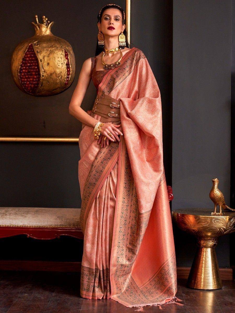 Elegant peach designer saree with intricate border, paired with gold jewelry and waist belt for ethnic wear