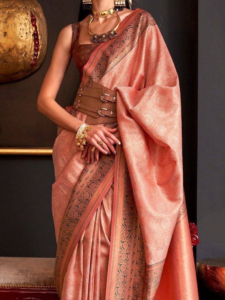 Elegant peach designer saree with intricate border, paired with gold jewelry and belt for ethnic wear