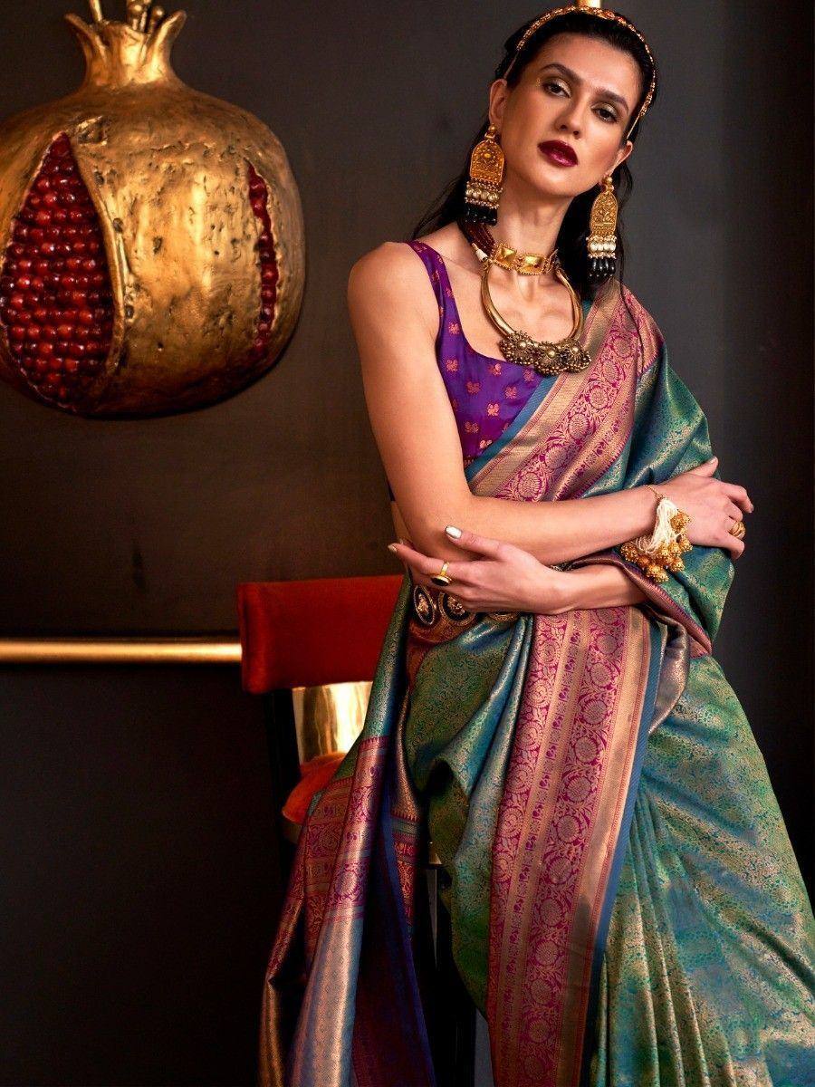 Woman in vibrant teal and purple designer saree with gold jewelry, ethnic wear for festive occasions