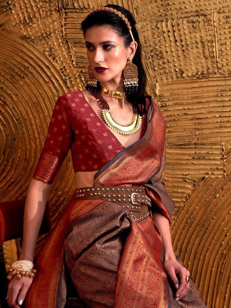 Elegant maroon and gold ethnic saree with designer blouse, traditional jewelry, and studded belt for festive occasions
