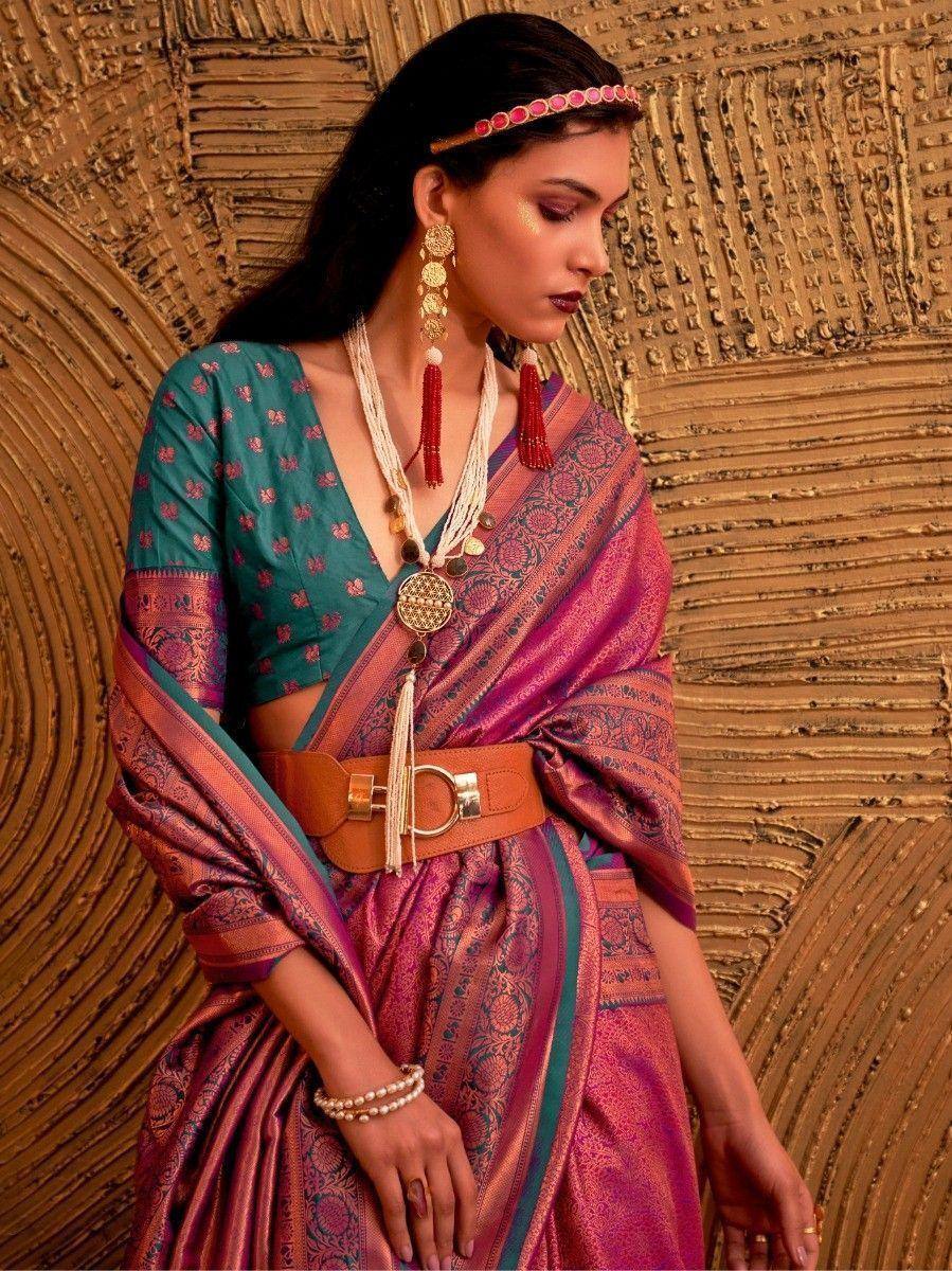 Woman in vibrant pink and teal ethnic saree with gold jewelry and belt, styled for Indian occasions