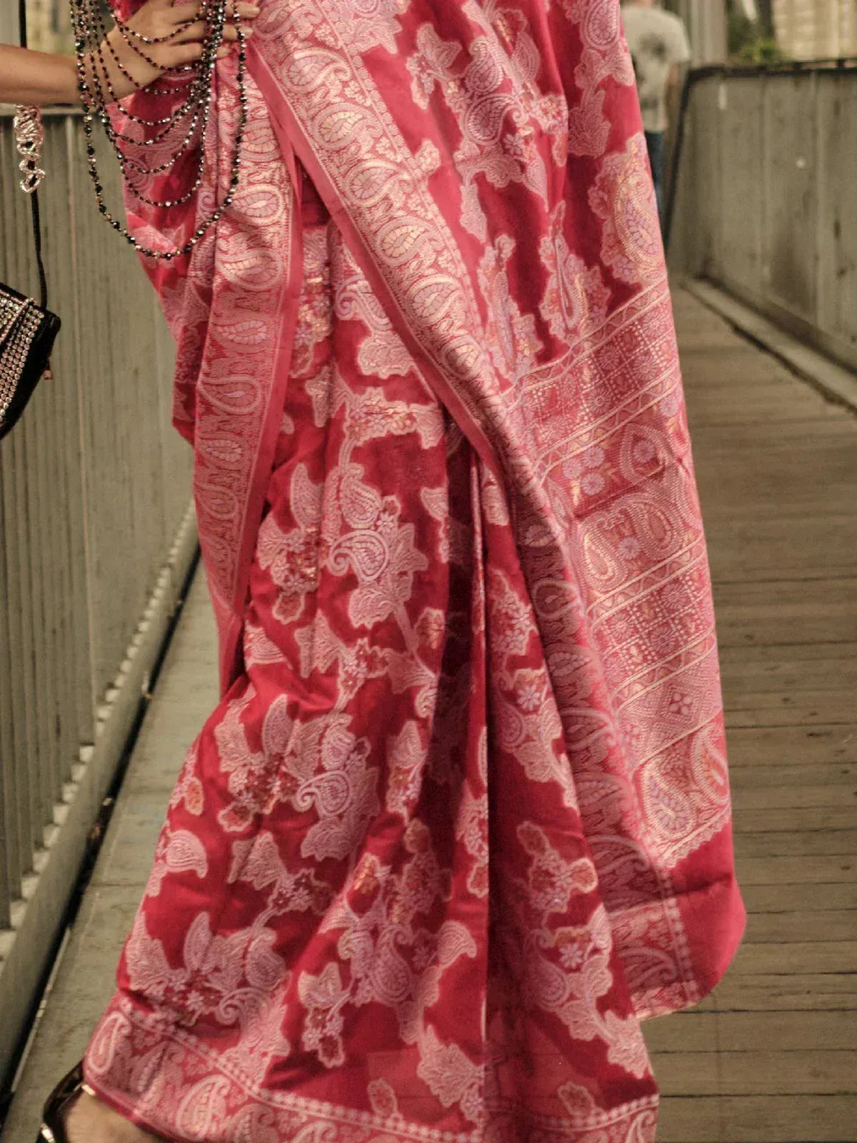 Red and pink paisley print Indian saree with intricate embroidery, styled with beaded accessories