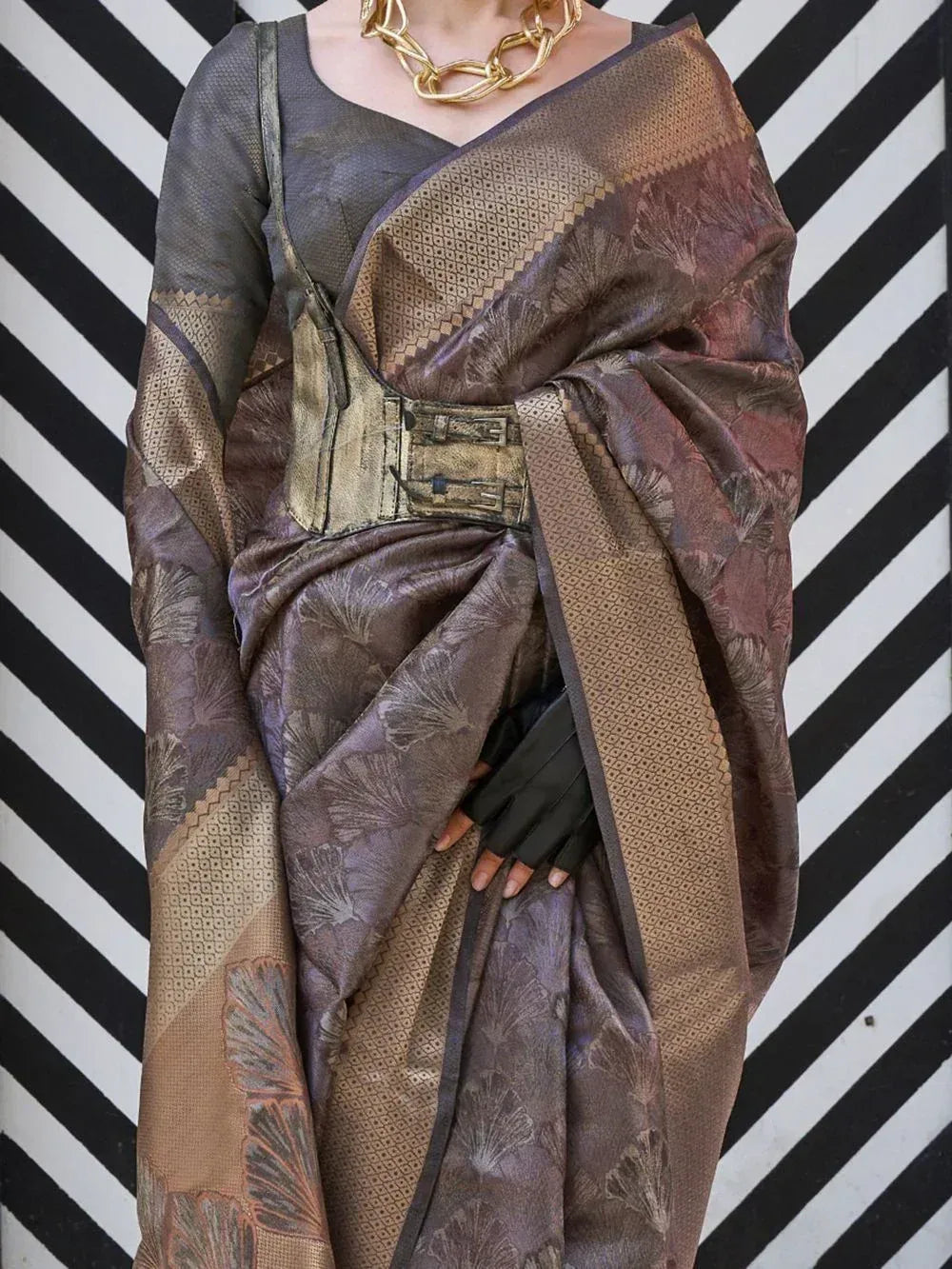 Elegant brown and gold designer saree with floral motifs, paired with a modern blouse and statement necklace