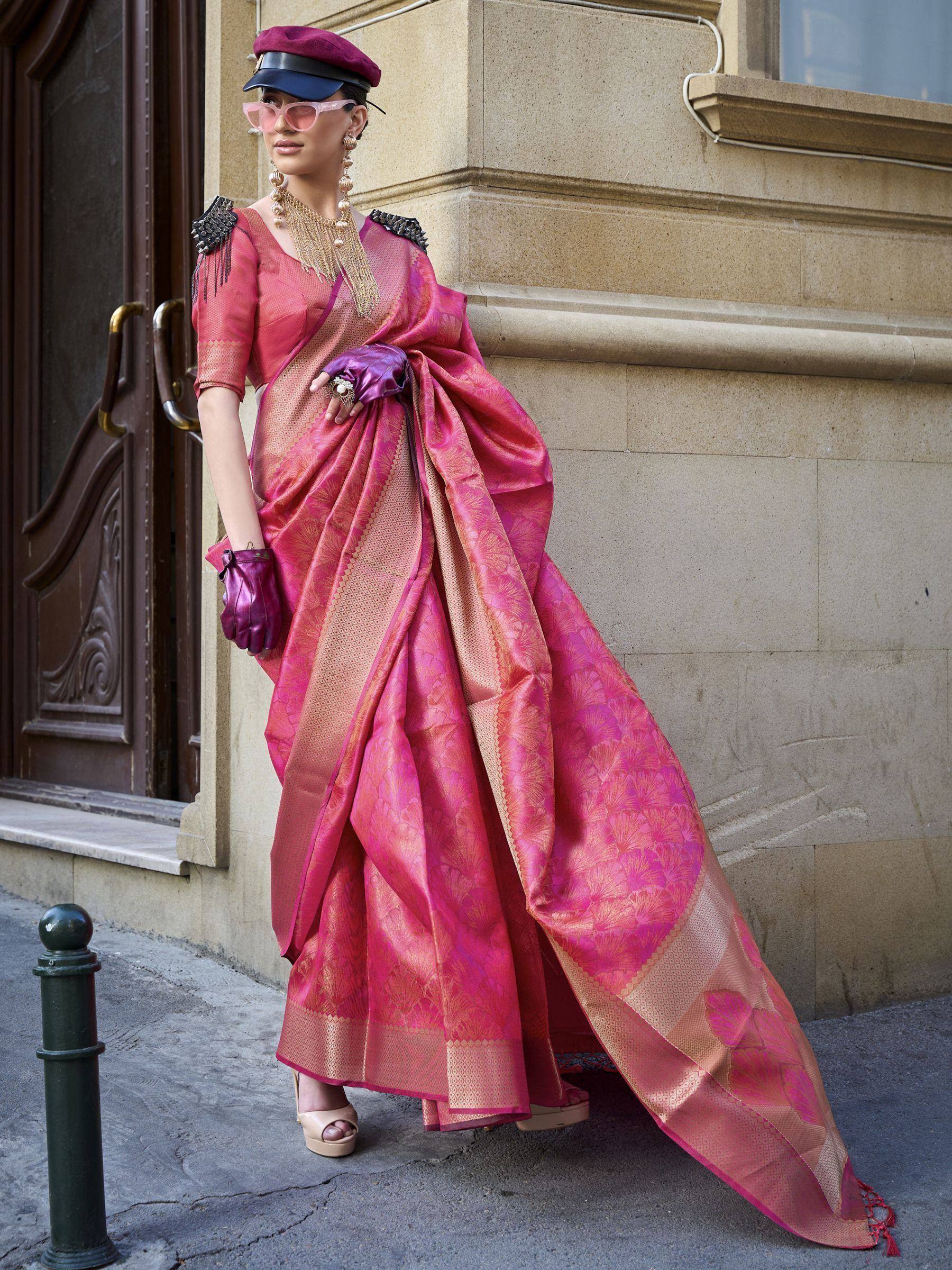 Woman in vibrant pink designer saree with gold motifs, styled with beret, gloves, and statement jewelry for ethnic fashion.