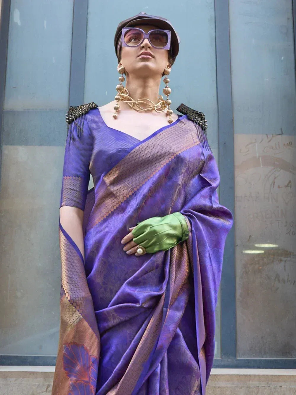 Purple designer saree with gold border, statement jewelry, and green gloves for ethnic fashion