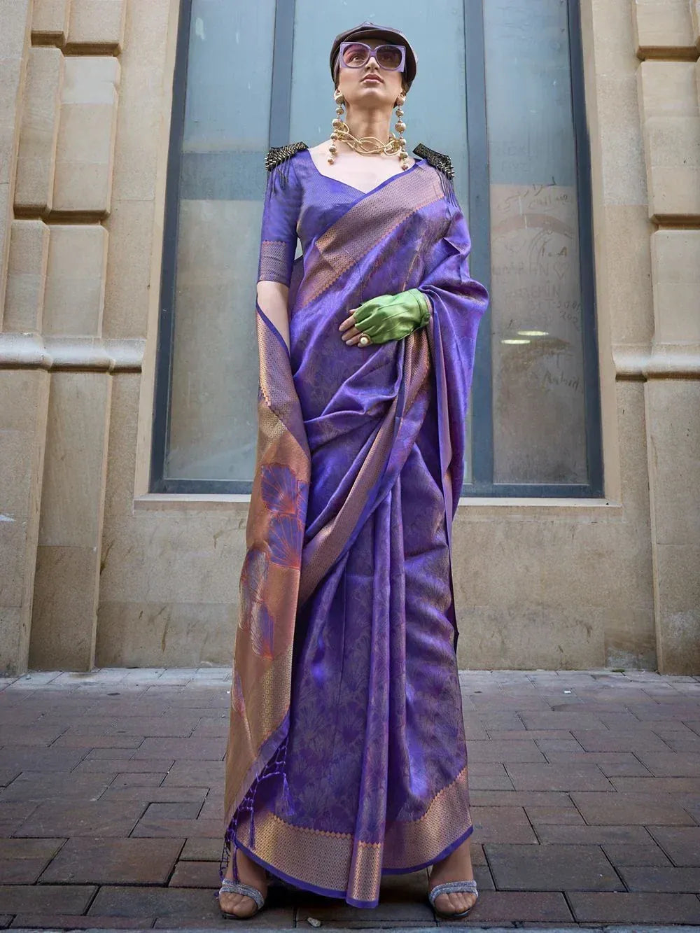 Purple designer saree with gold border, floral motifs, and embellished blouse, styled with green gloves and statement jewelry