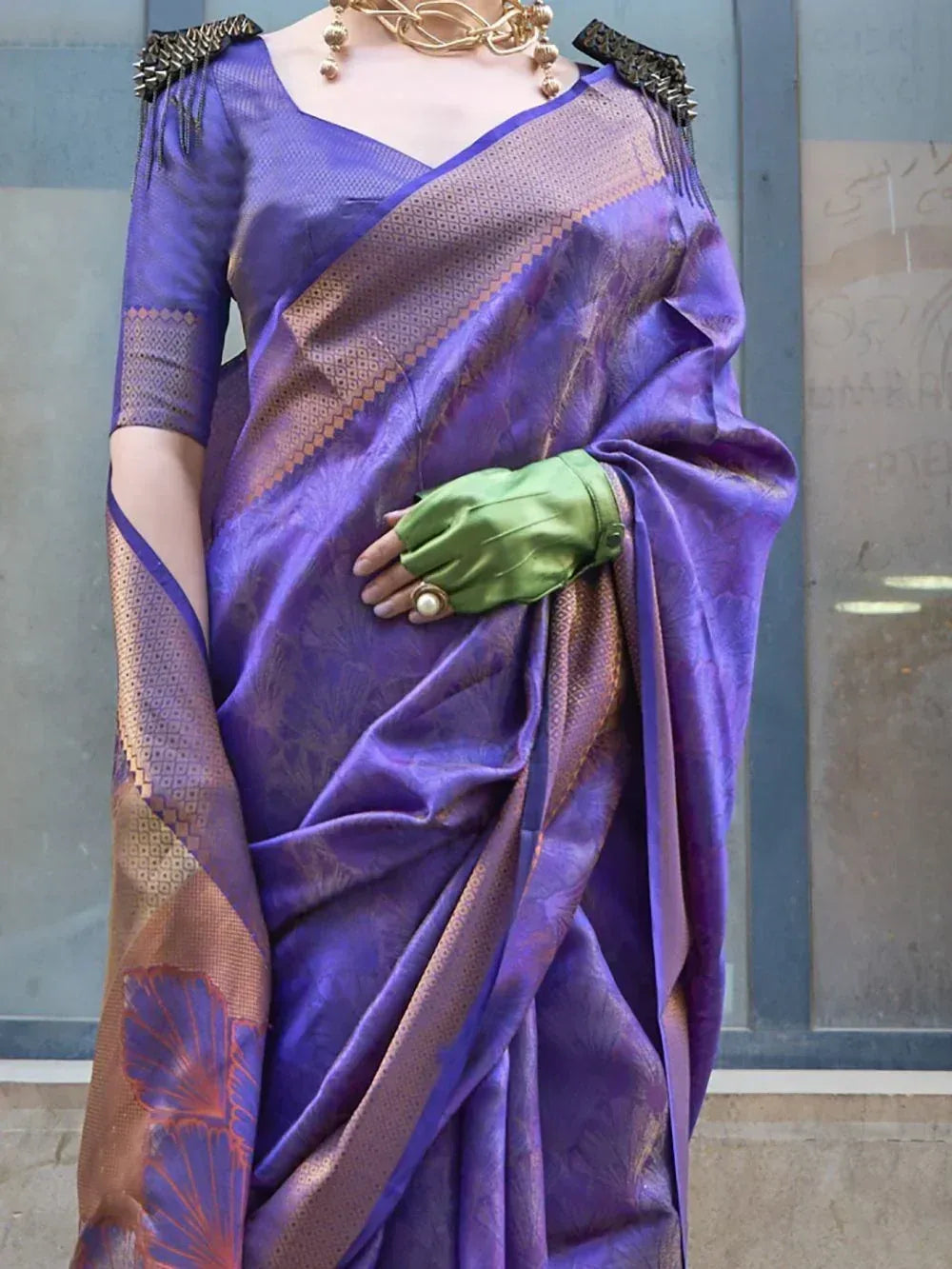 Purple silk saree with gold border and floral motifs, paired with green gloves and gold jewelry