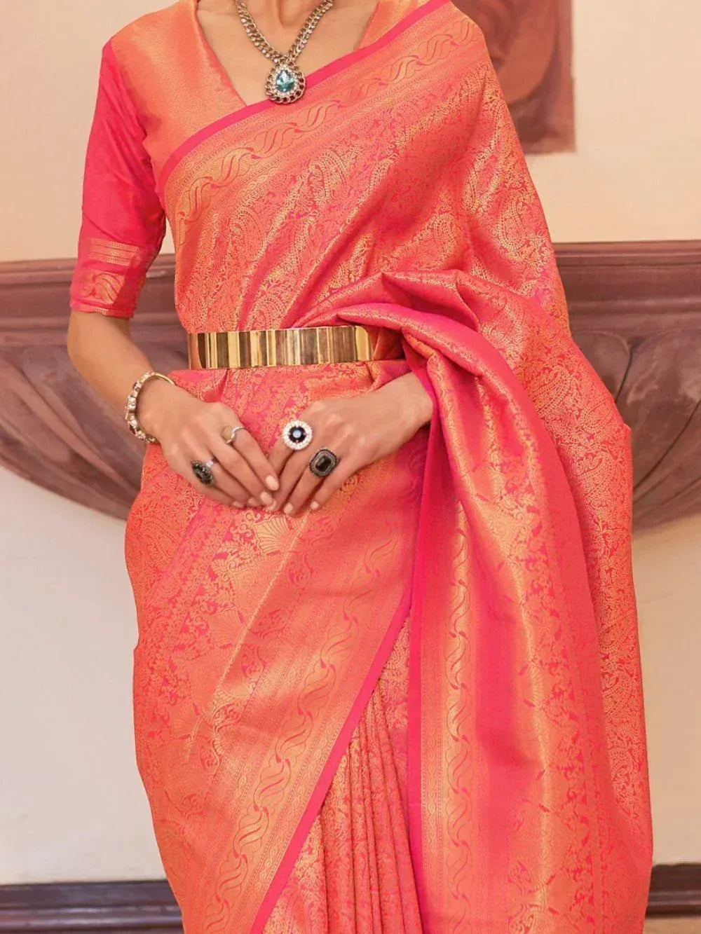 Pink and gold designer saree with intricate paisley weave, paired with statement jewelry and belt