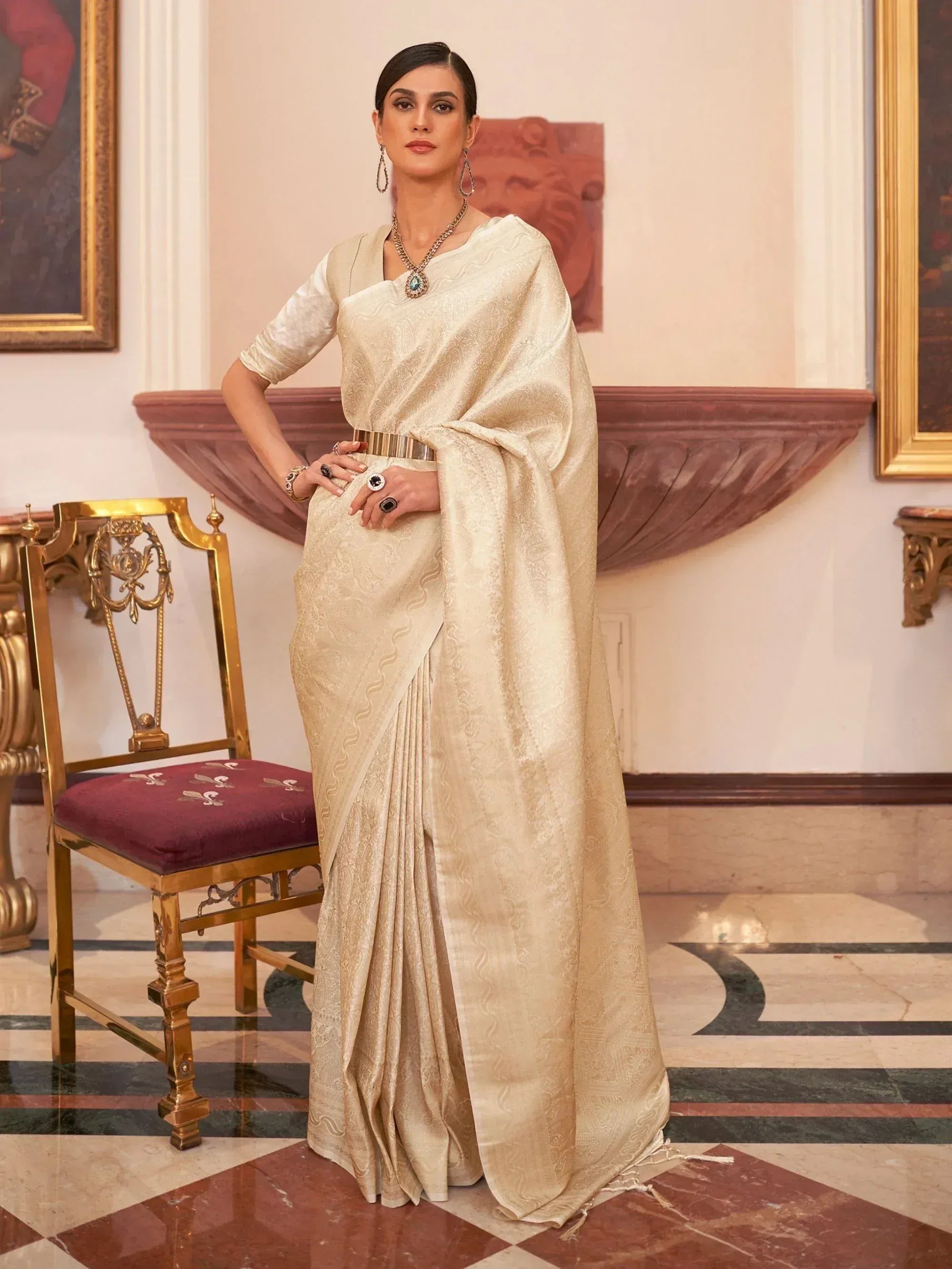 Elegant cream designer saree with intricate weave, paired with statement jewelry, perfect for Indian ethnic occasions.