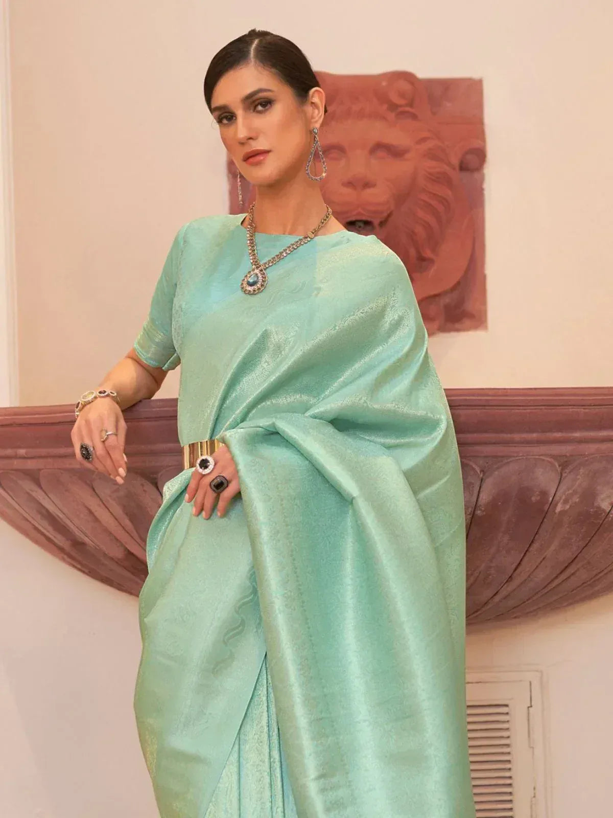 Mint green designer saree with gold belt and statement jewelry for ethnic wear