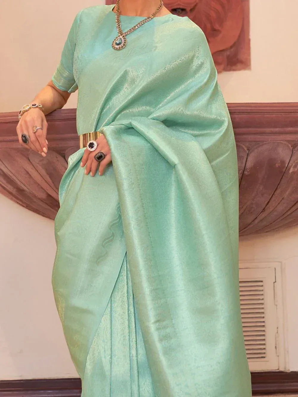 Mint green designer saree with subtle sheen, paired with statement jewelry for ethnic occasions